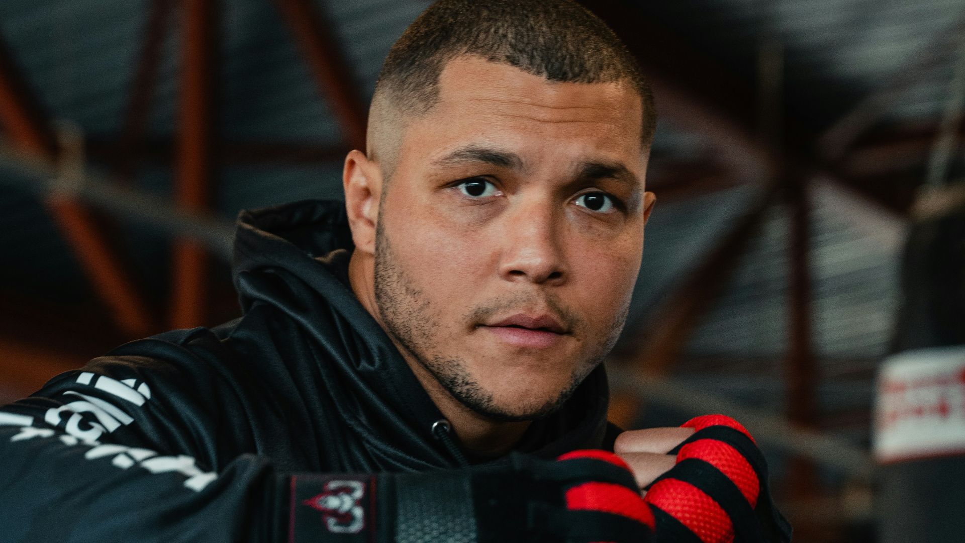 A man in a black jacket and red gloves