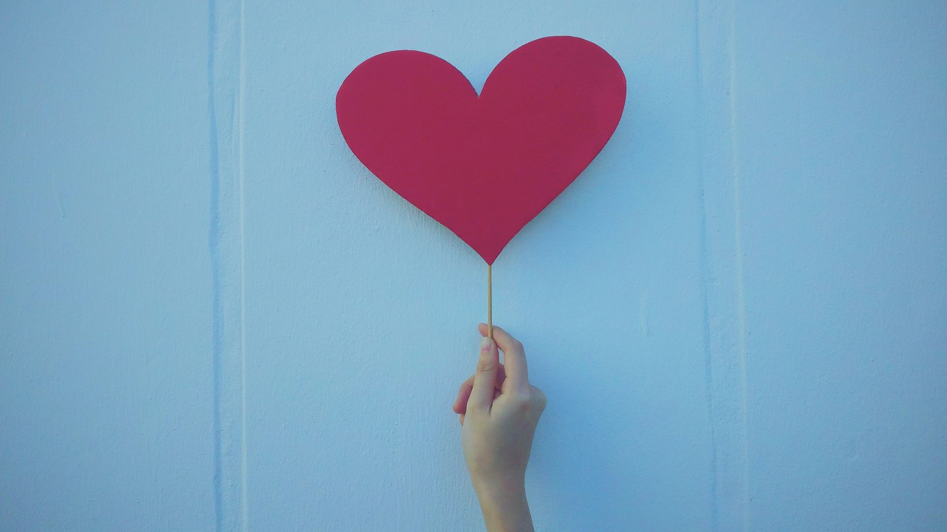 person holding heart shaped red balloon