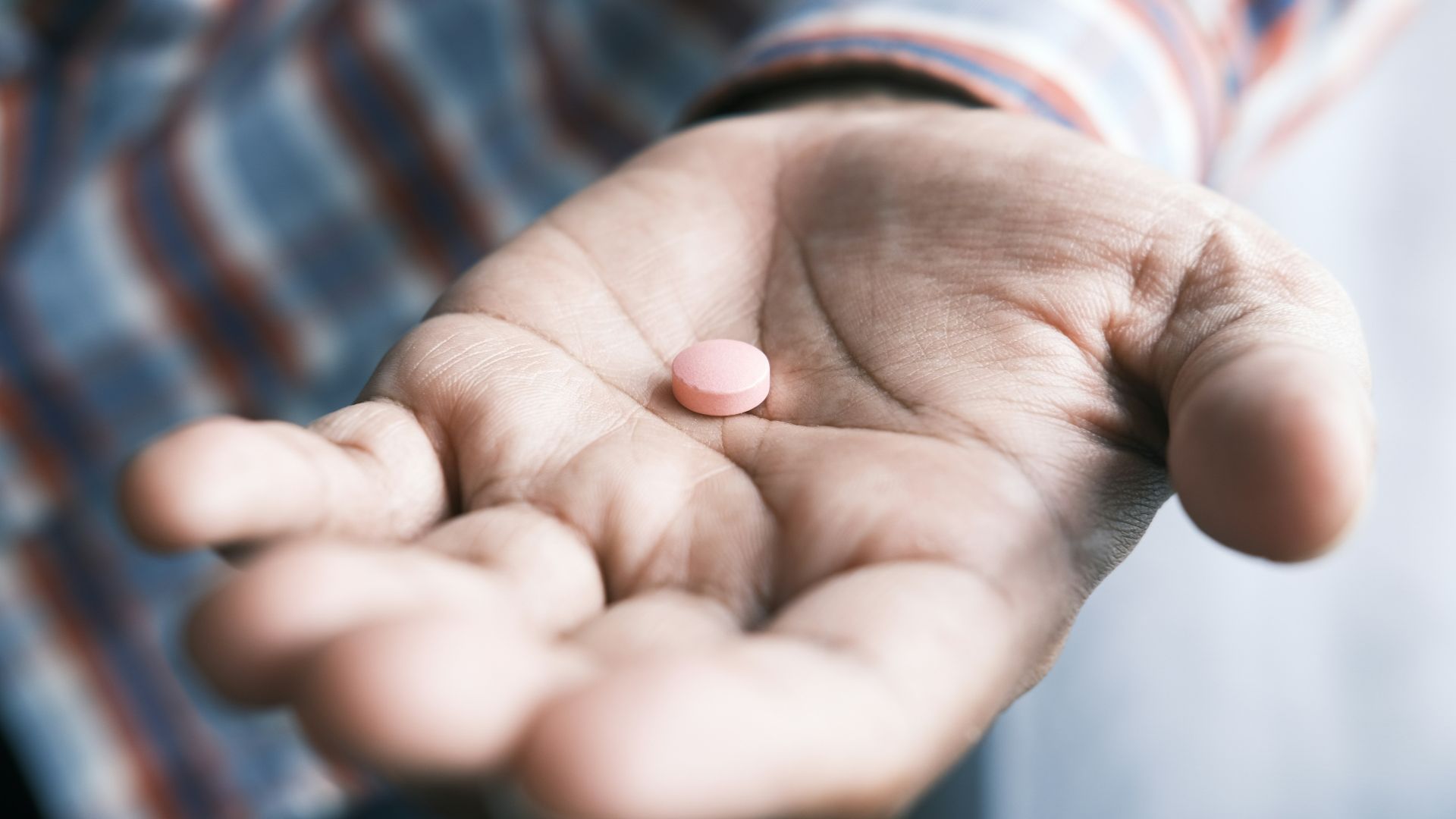 person holding pink round medication pill