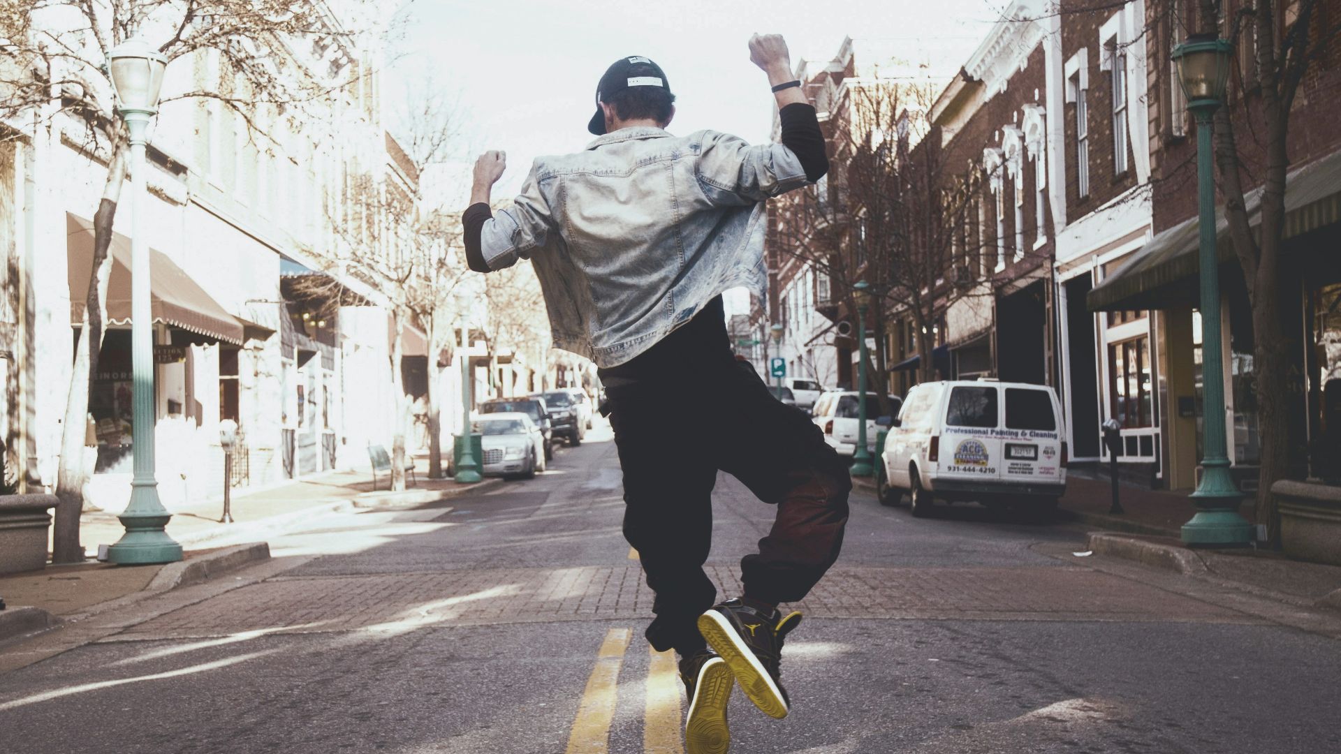 man jumping on the middle of the street during daytime