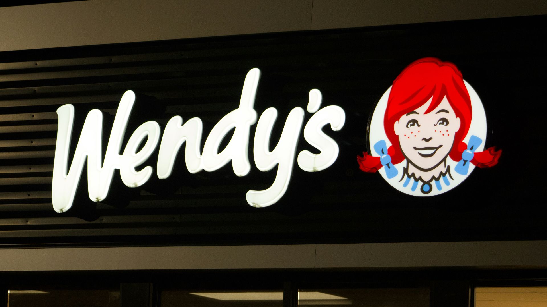 A wendy's sign is lit up at night