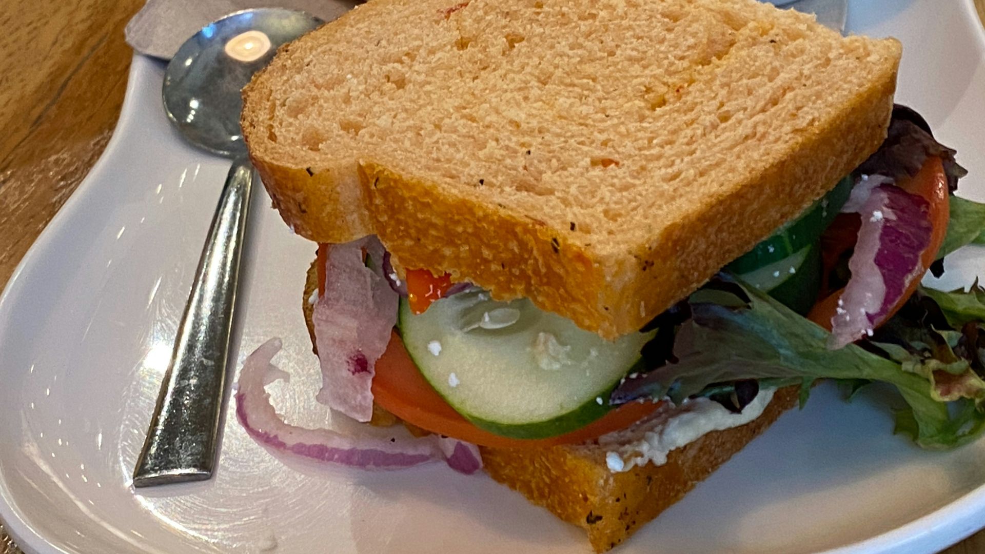 A white plate topped with a sandwich and a bowl of soup