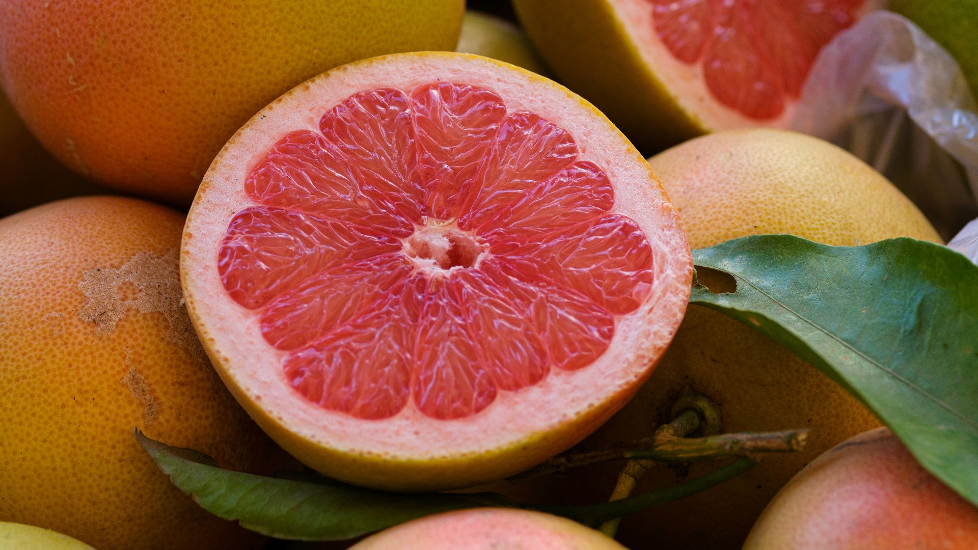 a pile of grapefruits with one cut in half