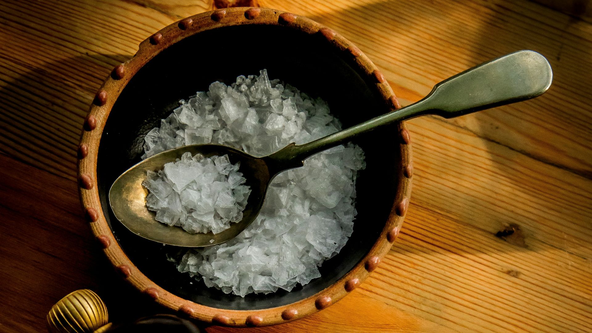 a wooden bowl filled with white rice next to a bottle