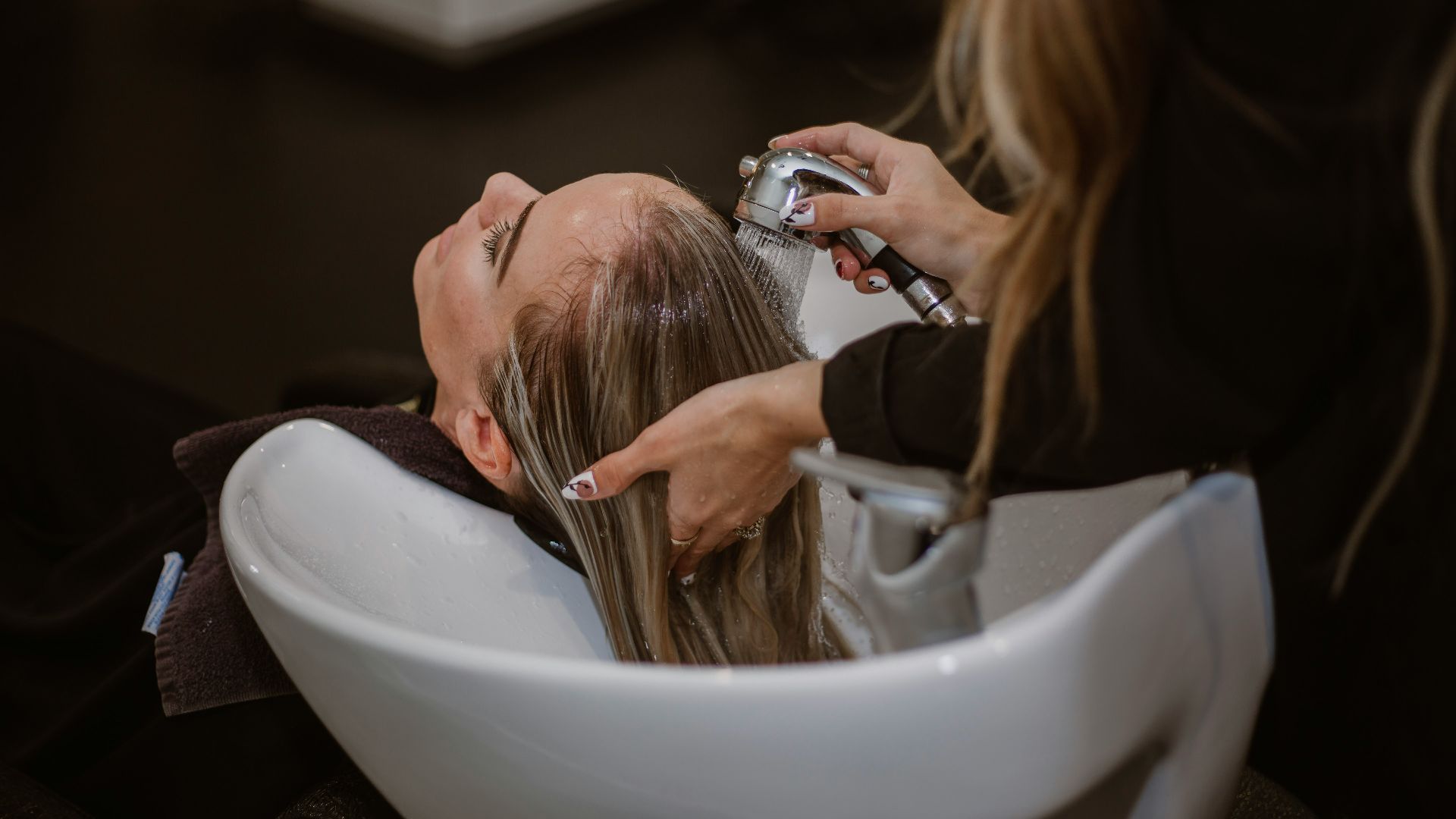 a woman getting her hair cut by a hair stylist