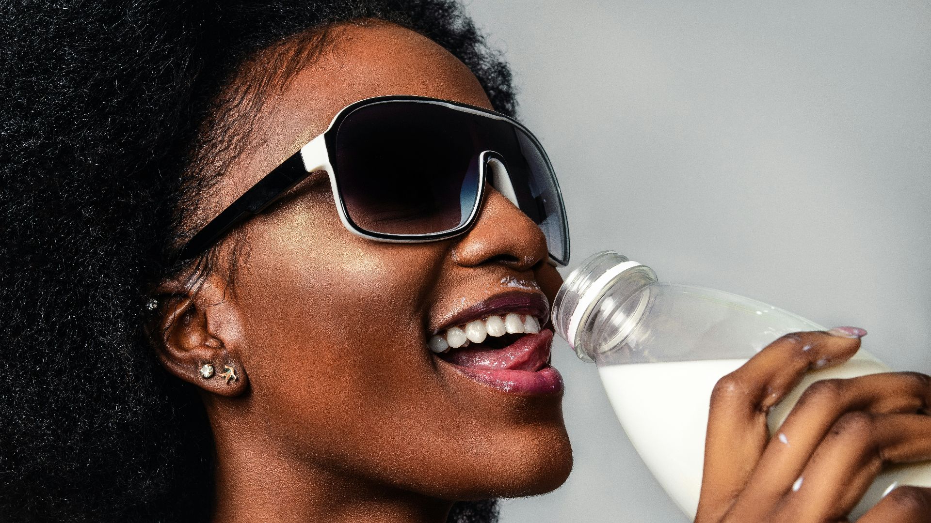 woman wearing black and white sunglasses drinking milk