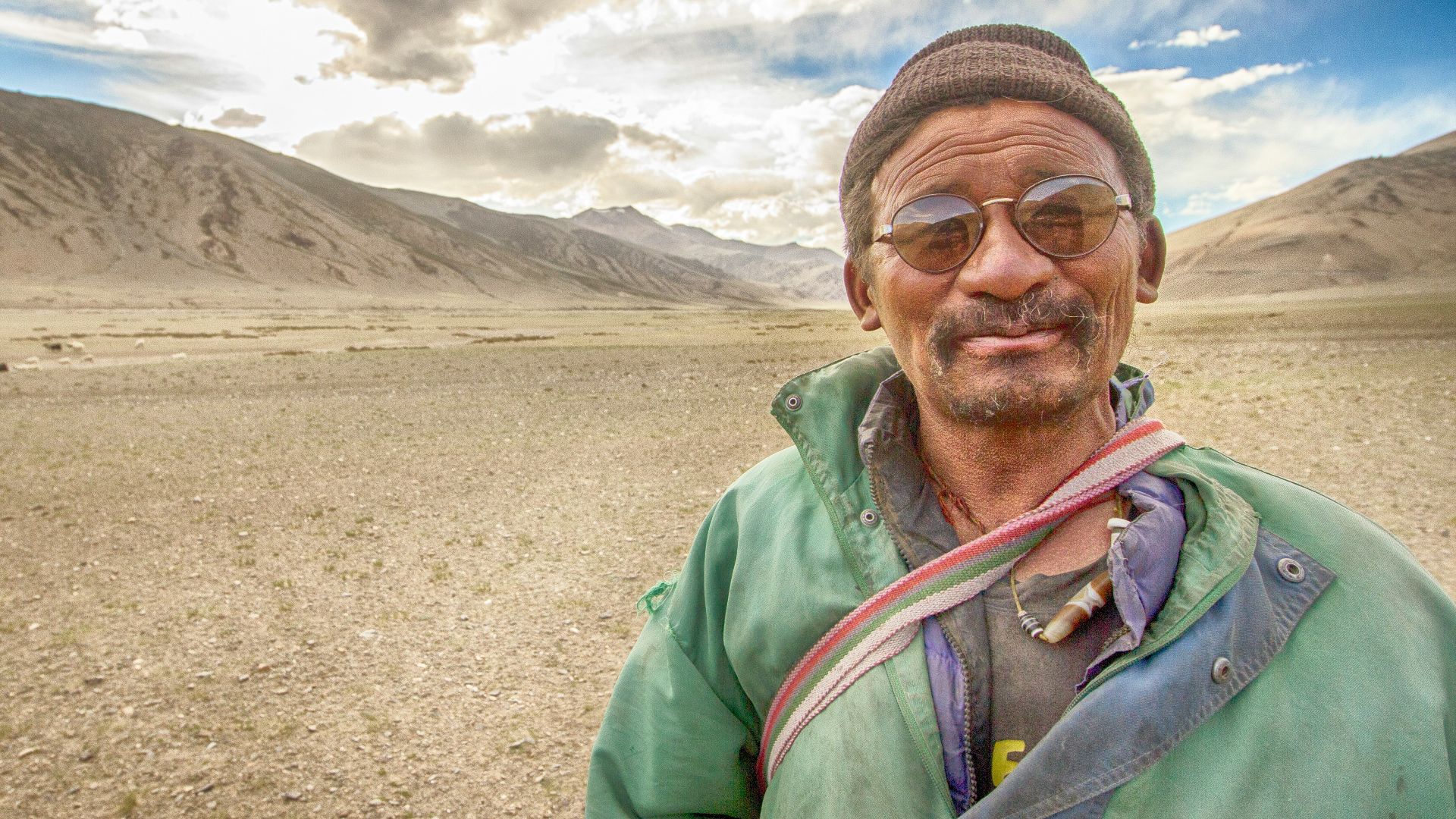 man in green jacket wearing black knit cap and sunglasses