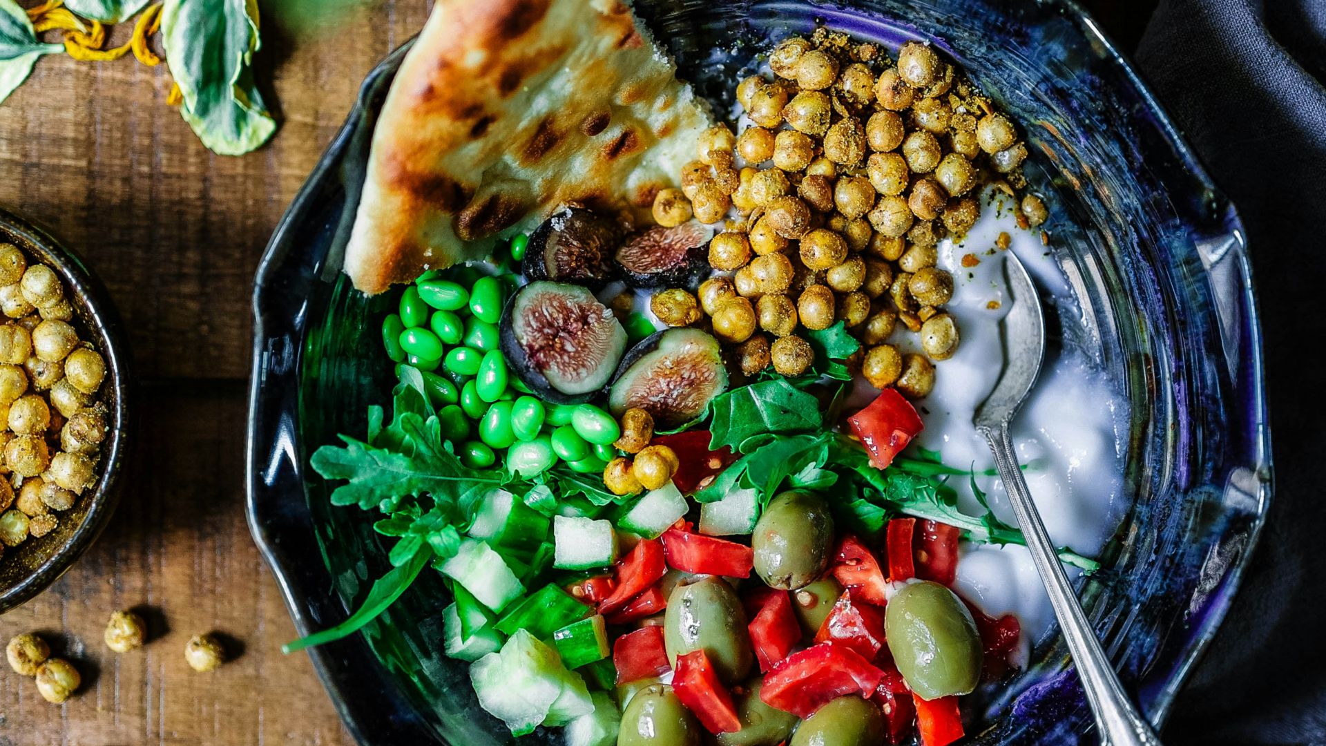 silver spoon on black ceramic bowl with vegetables