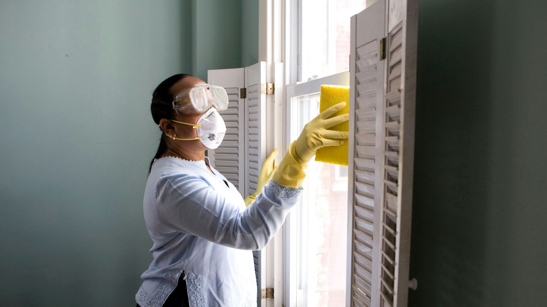 woman in white long sleeve shirt and blue denim jeans standing beside white wooden framed glass