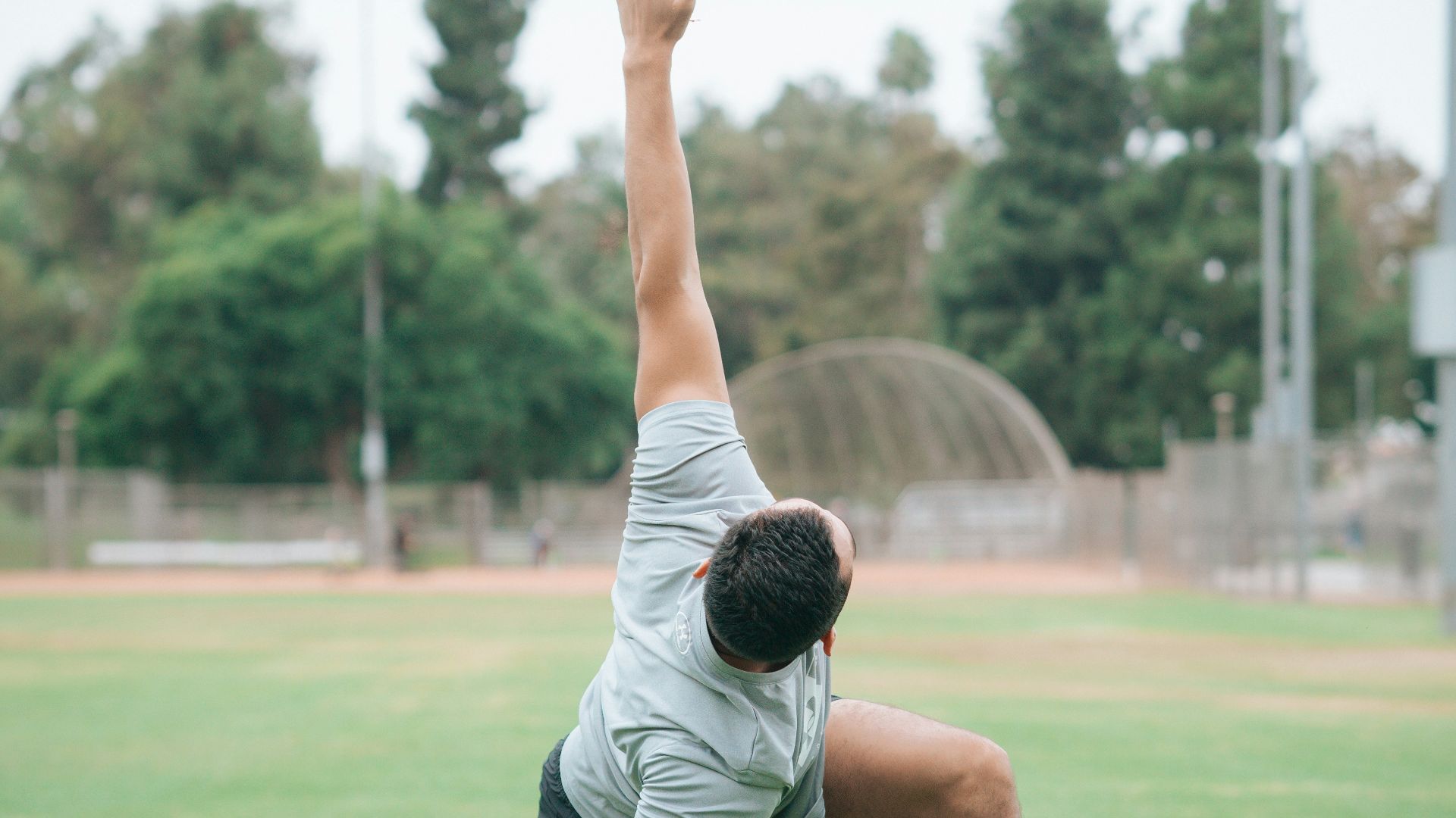 man in black and white t-shirt and black shorts sitting on green grass field during