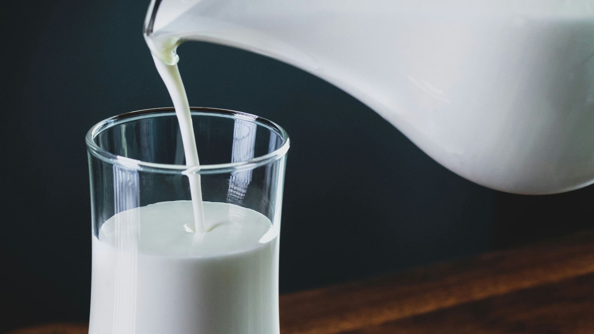 person pours milk into glass