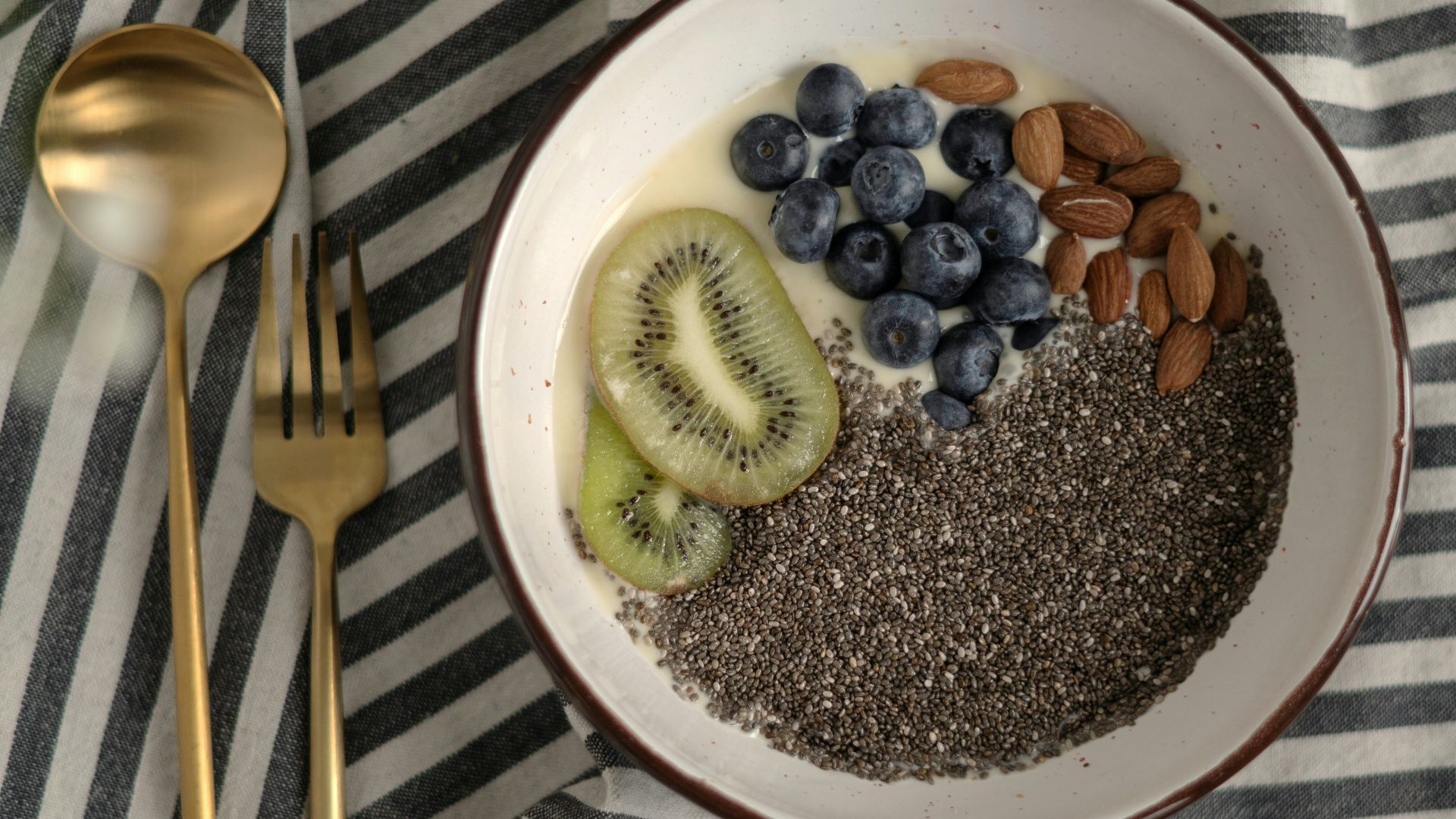a bowl of cereal with kiwis, bananas, and blueberries