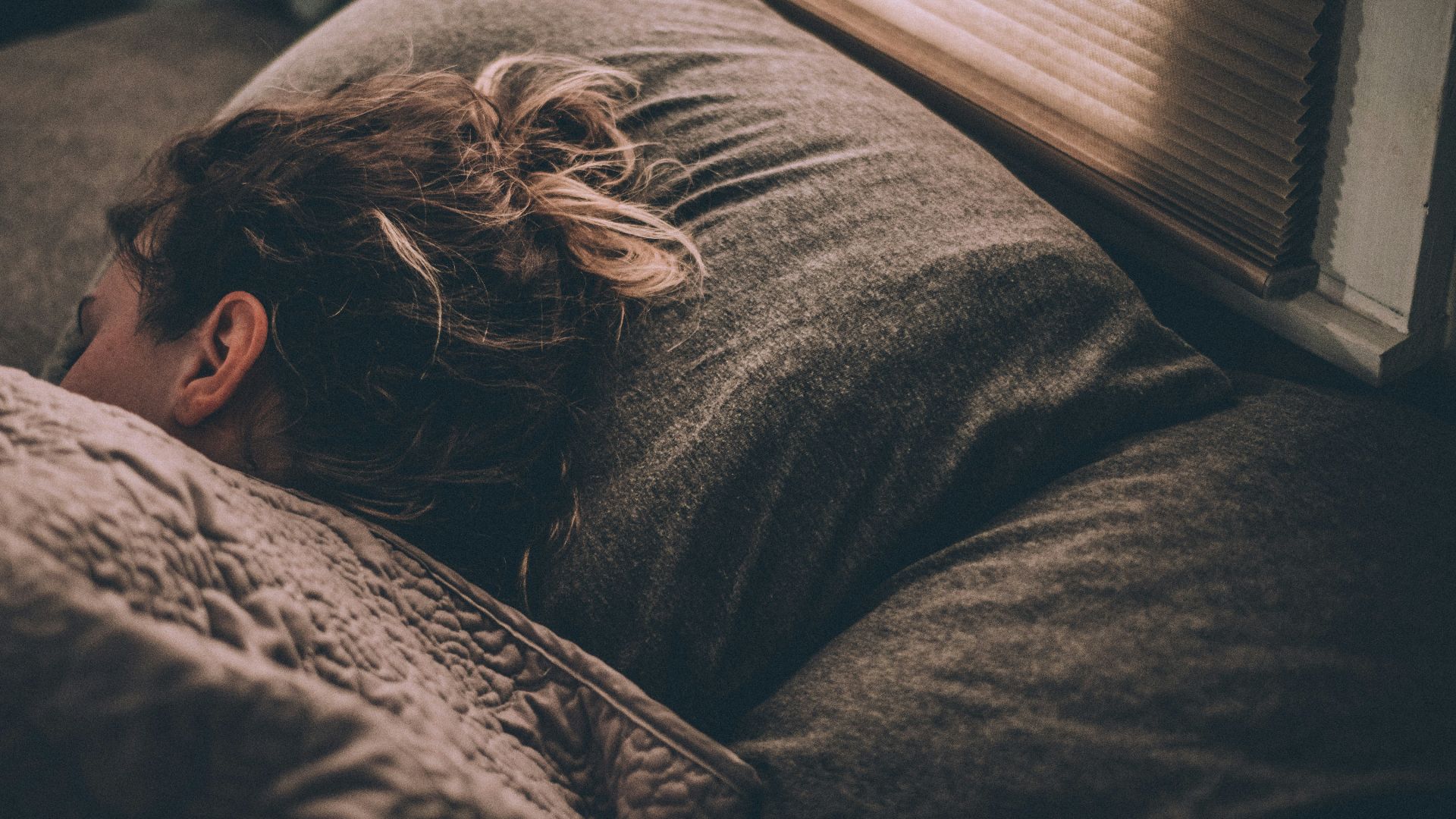 woman sleeping on bed under blankets