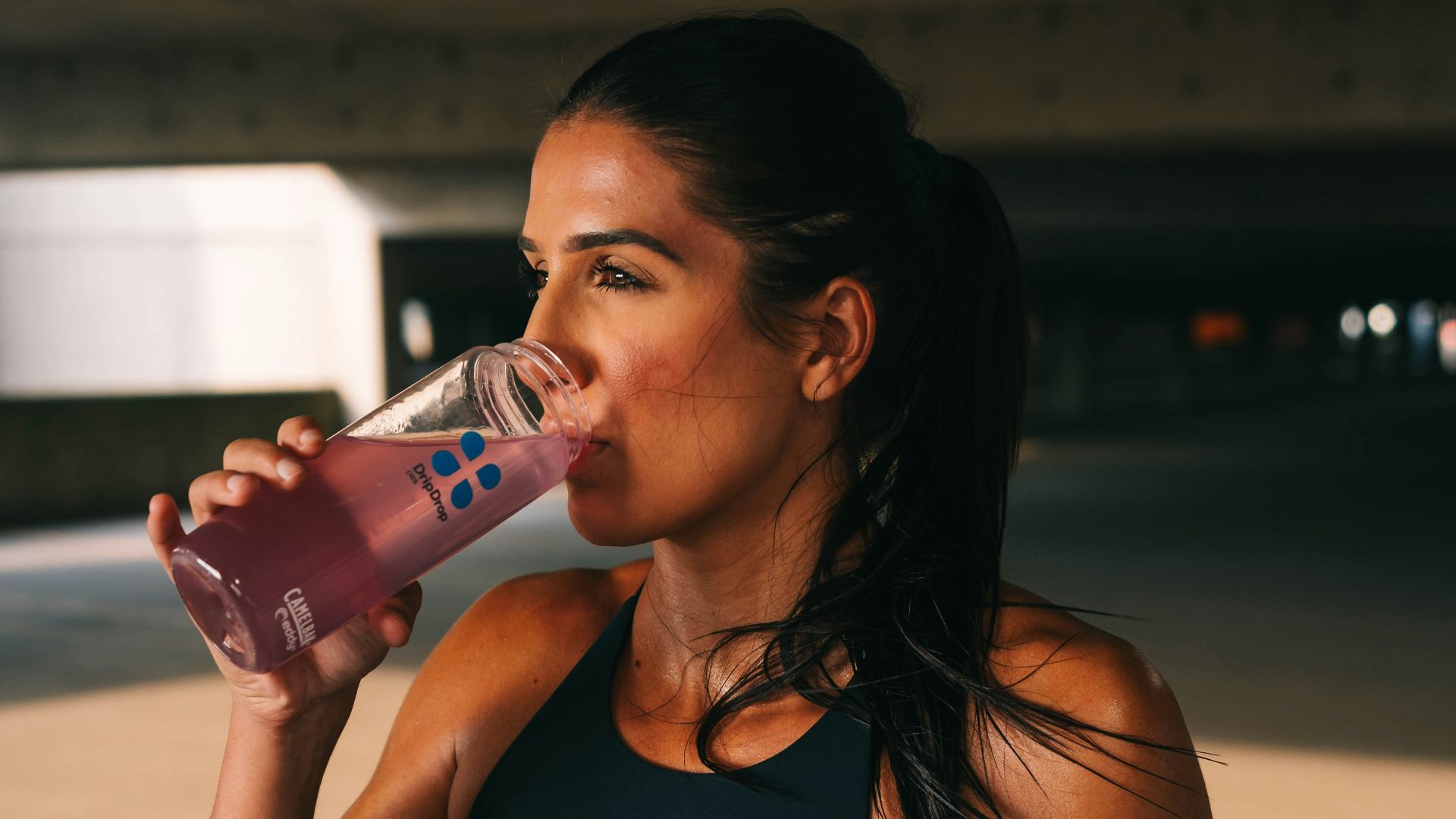 a woman in a sports bra top drinking from a bottle