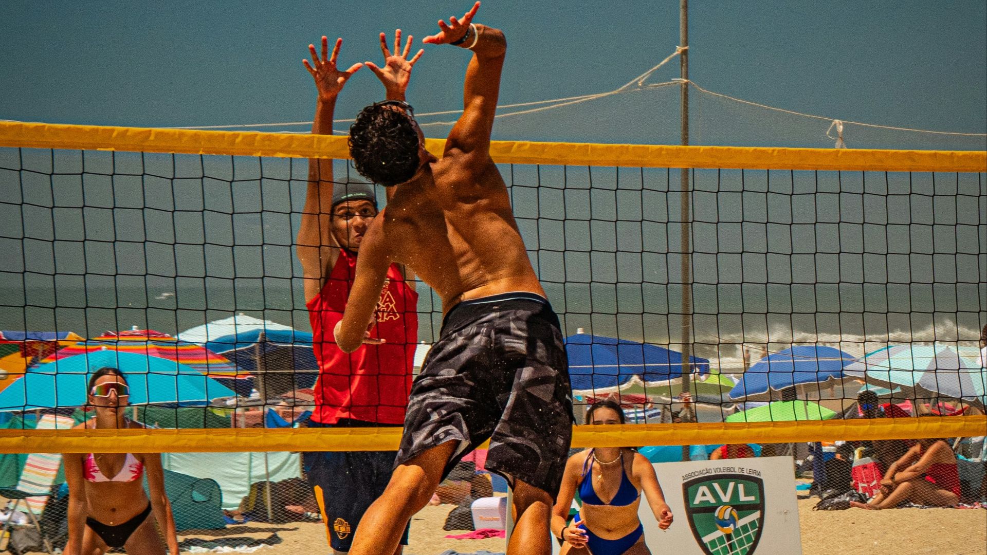 Beach volleyball players jumping to hit ball