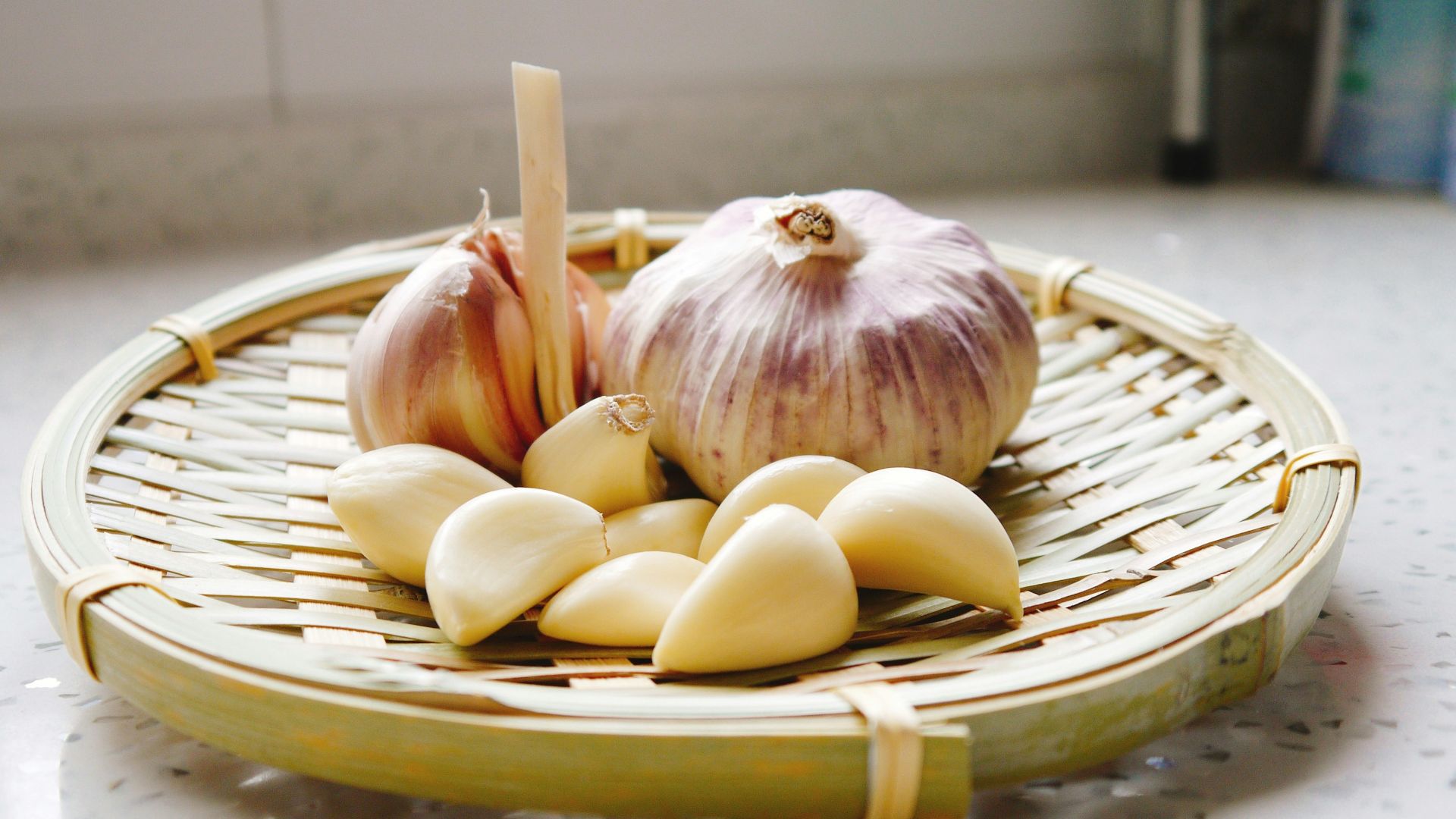 a basket of garlic and garlic bulbs on a counter