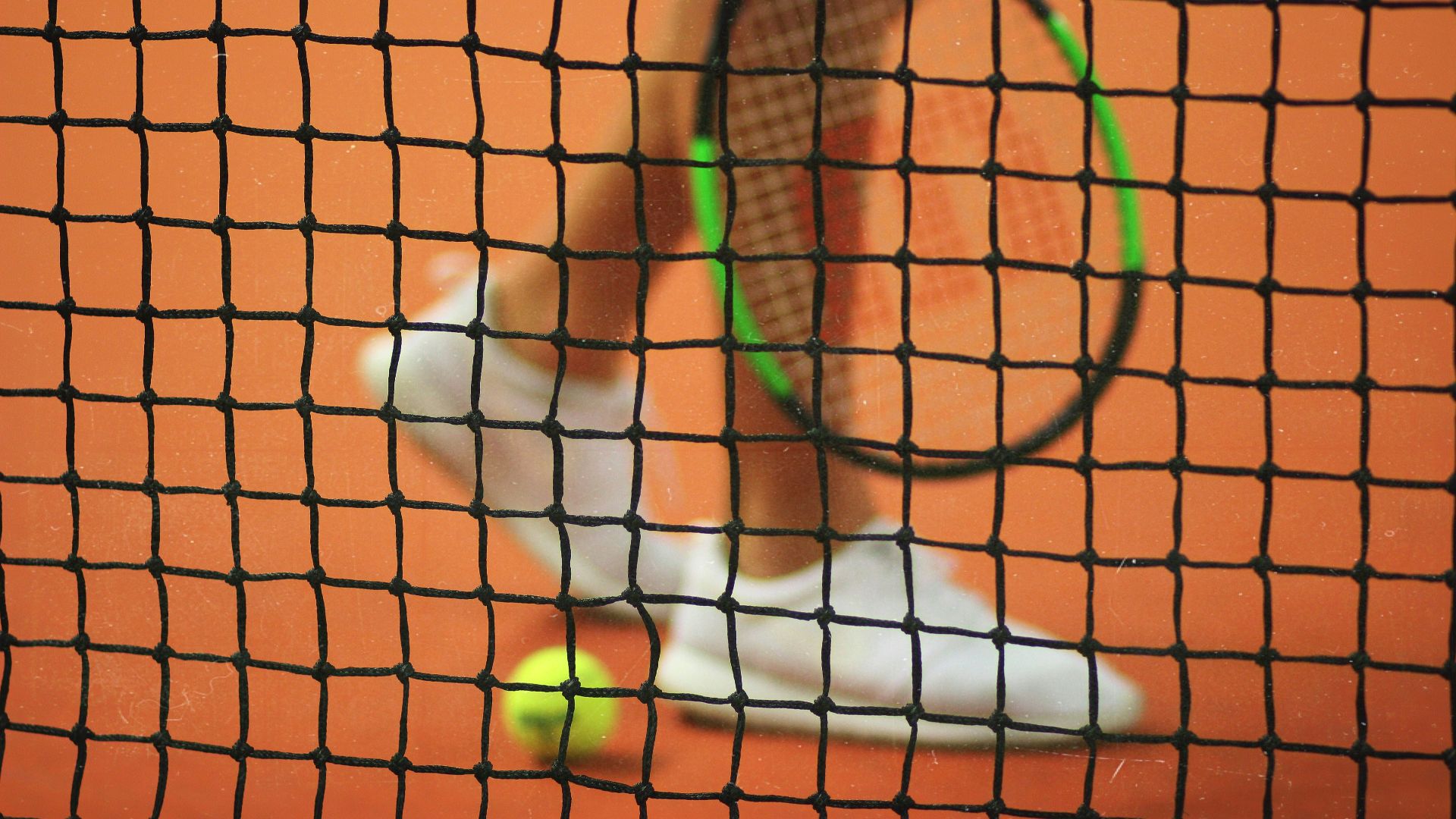 person wearing pair of white low-top sneakers while holding Wilson tennis racket