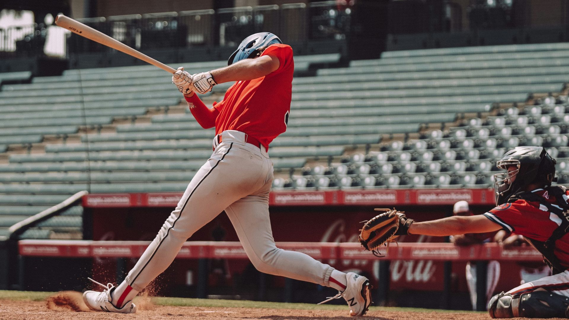 woman in red jersey shirt and white shorts holding baseball bat