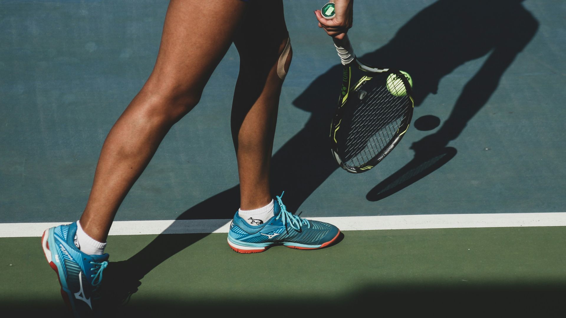 woman holding tennis ball and racket