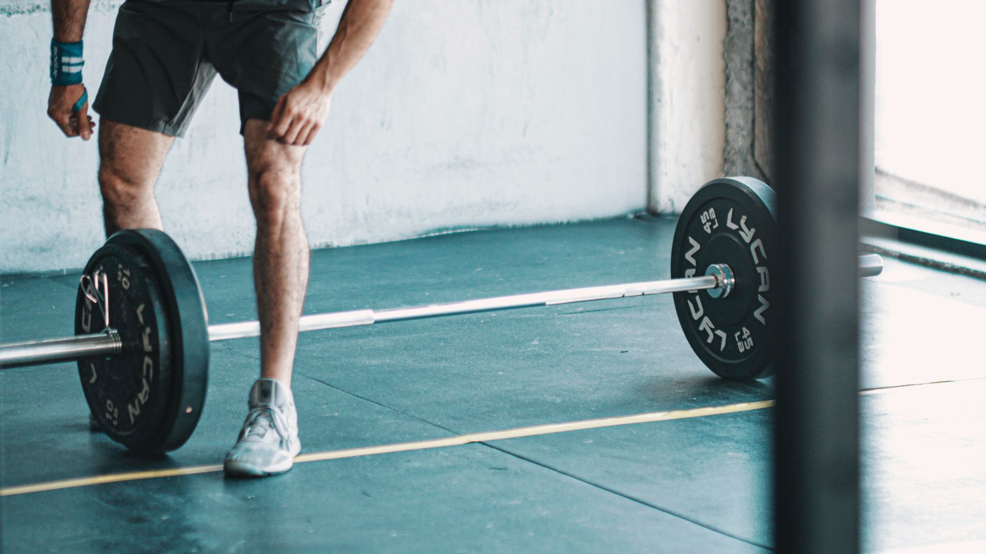 man in black t-shirt and black shorts holding black barbell