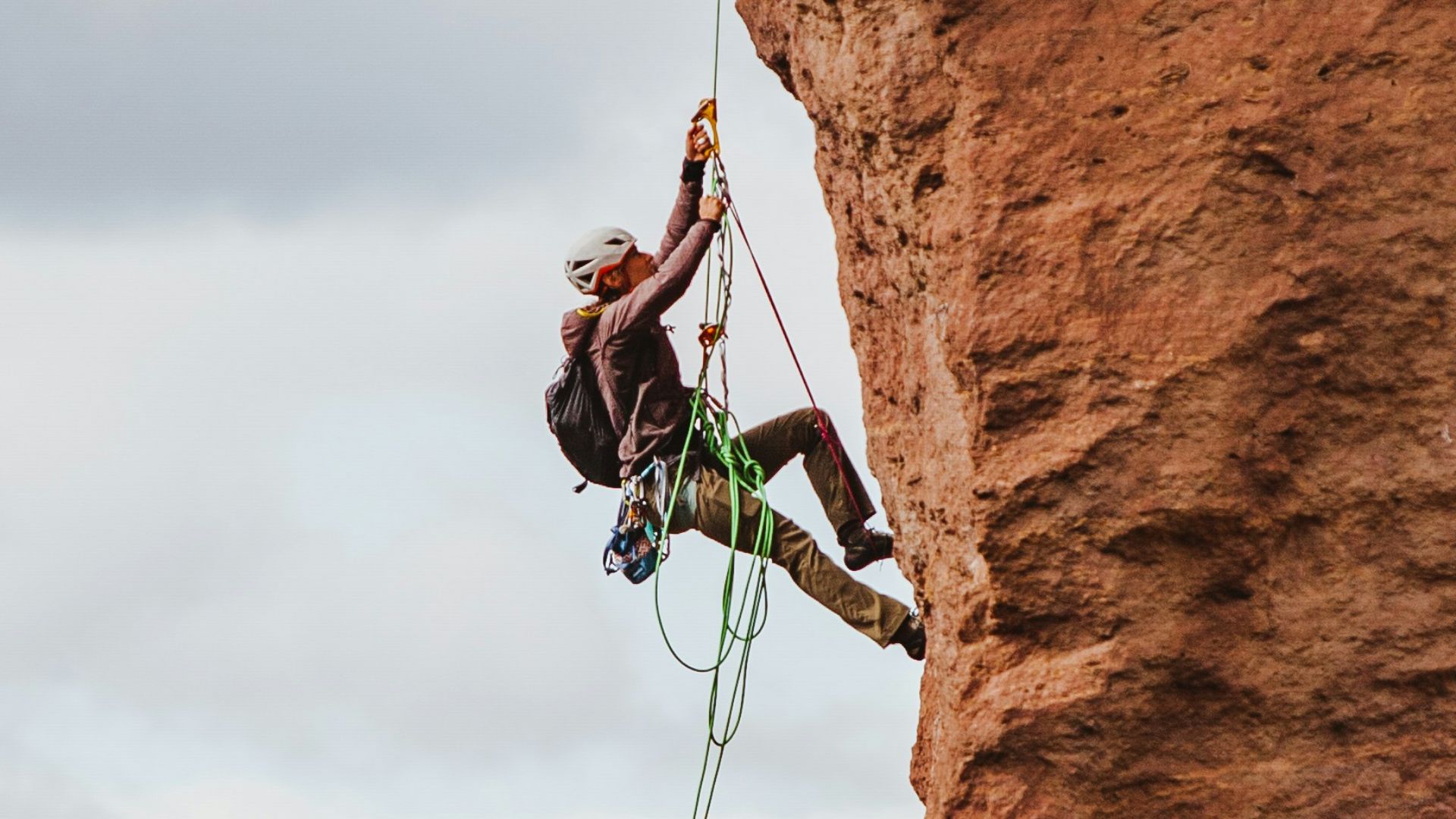 man in black shorts climbing brown rock formation during daytime