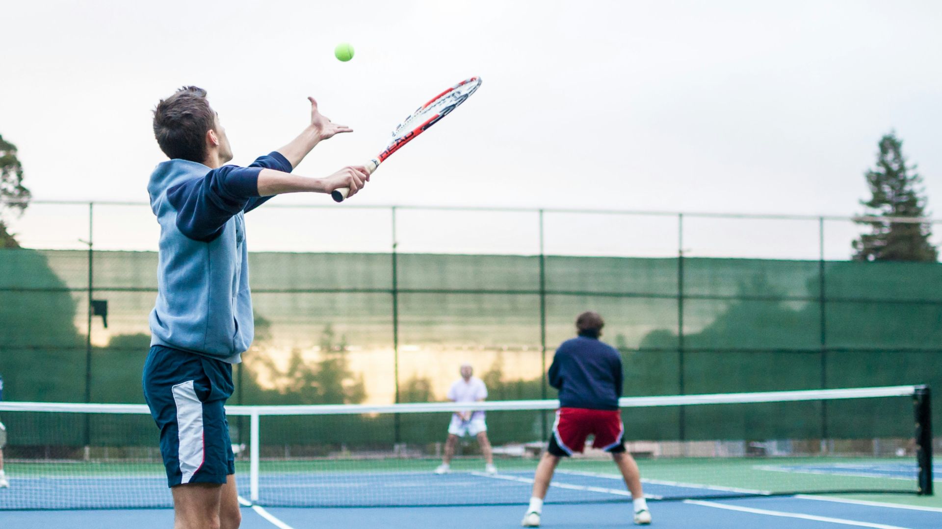 four men playing double tennis during daytime
