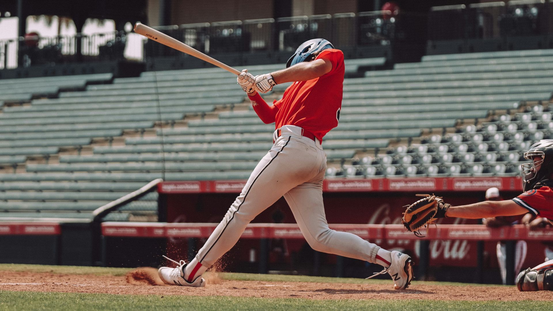 woman in red jersey shirt and white shorts holding baseball bat