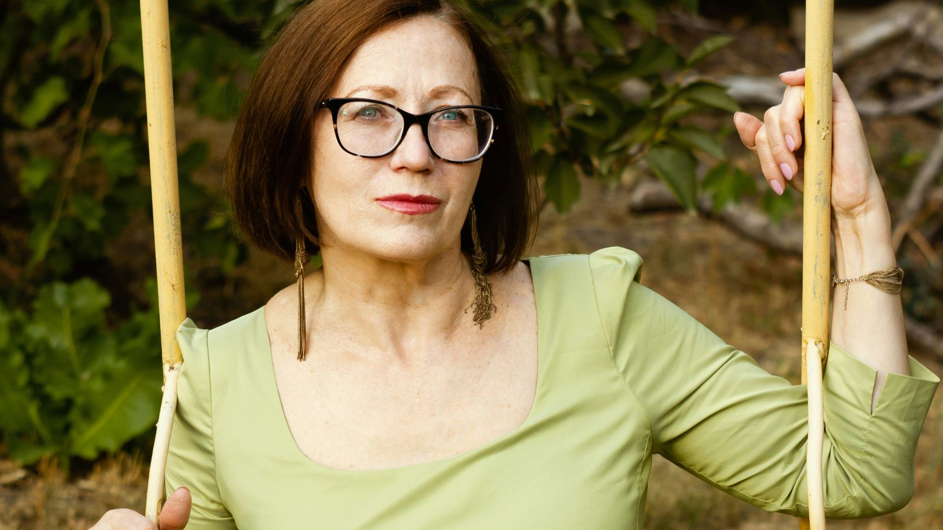 A woman in a green dress sitting on a swing