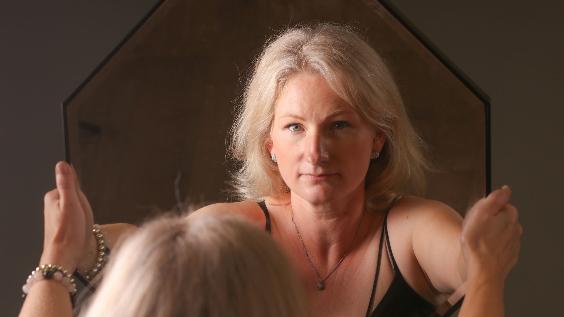 A woman standing in front of a mirror brushing her hair