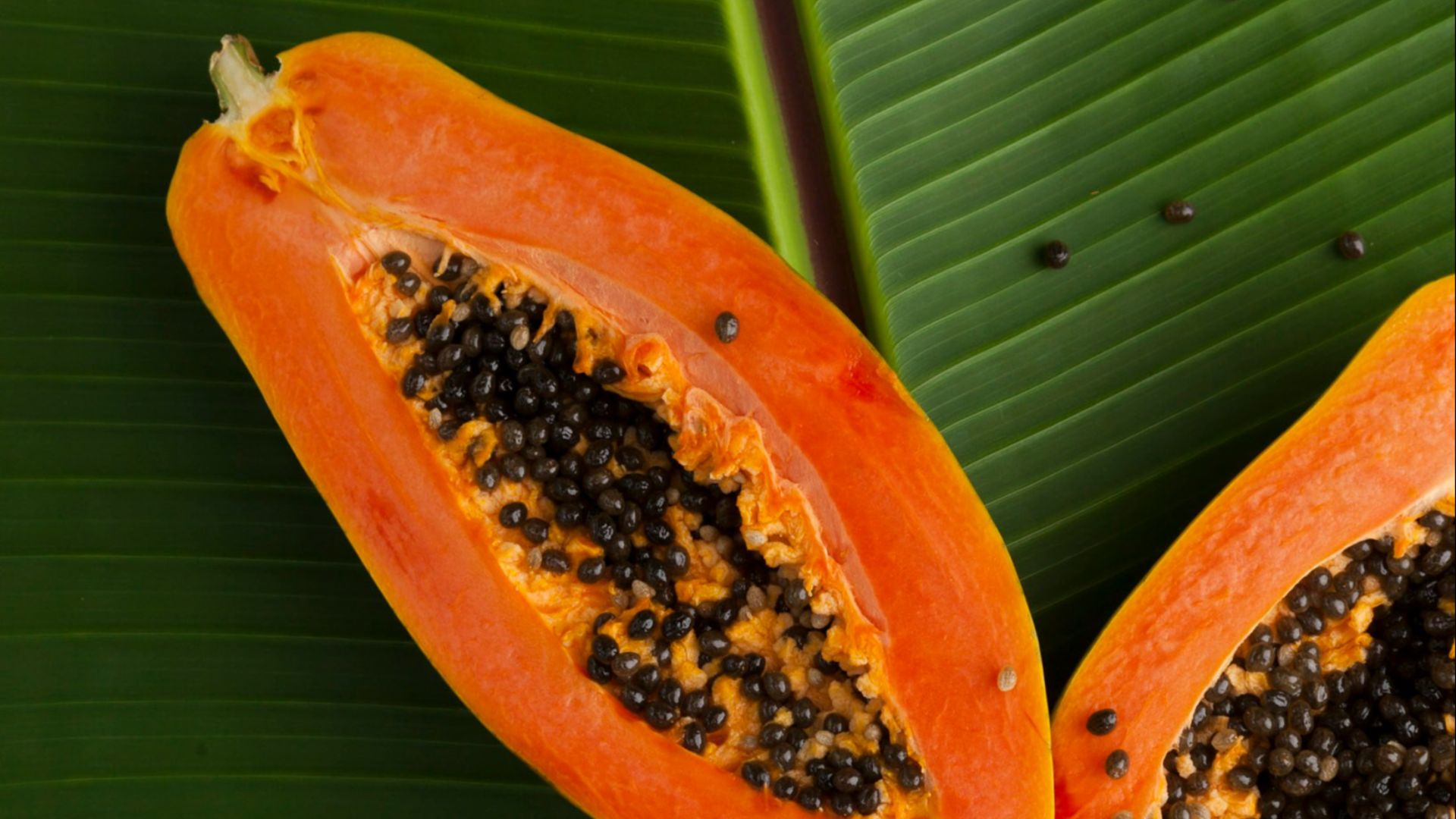 sliced papaya on green banana leaf