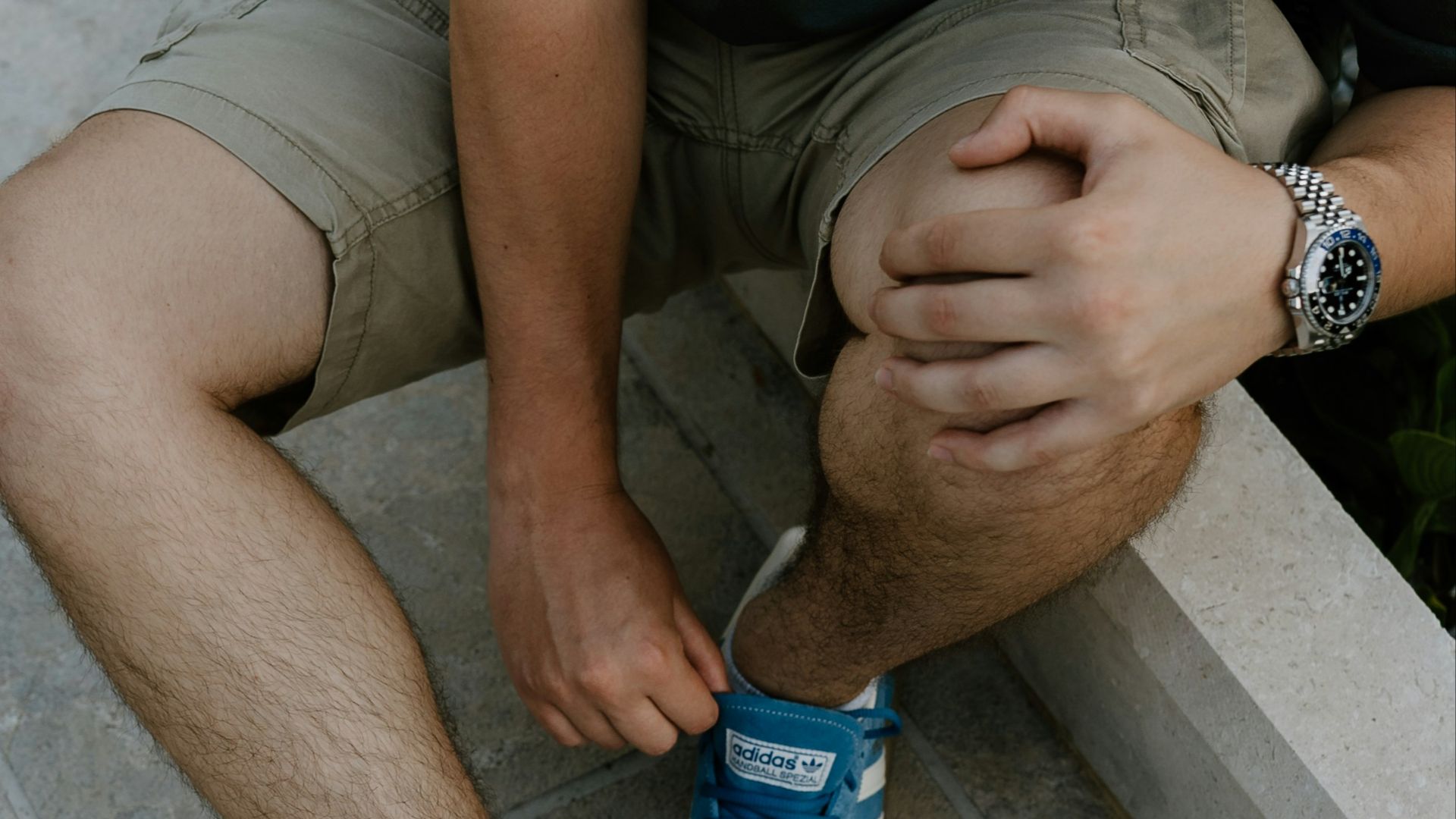 A man sitting on a ledge tying his shoes