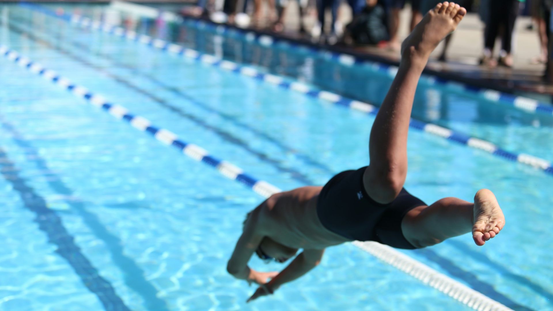 woman in black one piece swimsuit jumping on swimming pool during daytime