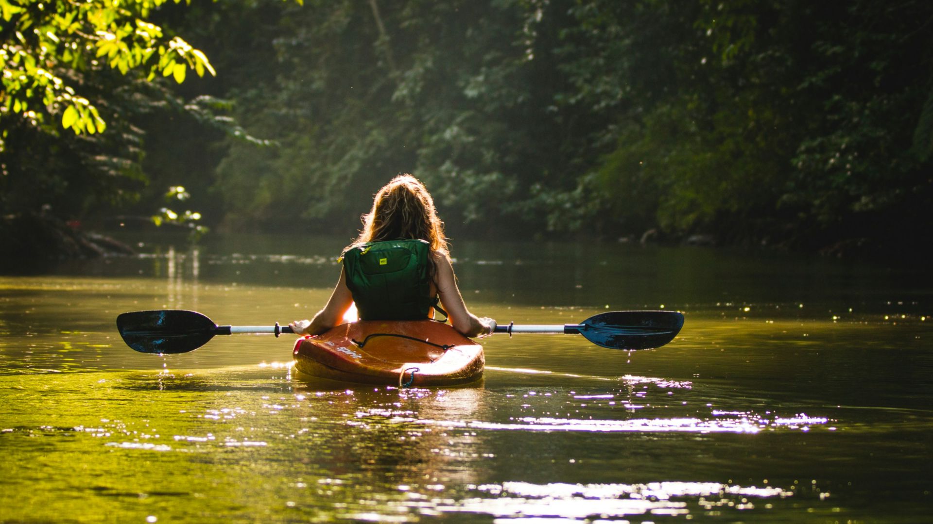 woman on kayak on body of water holding paddle