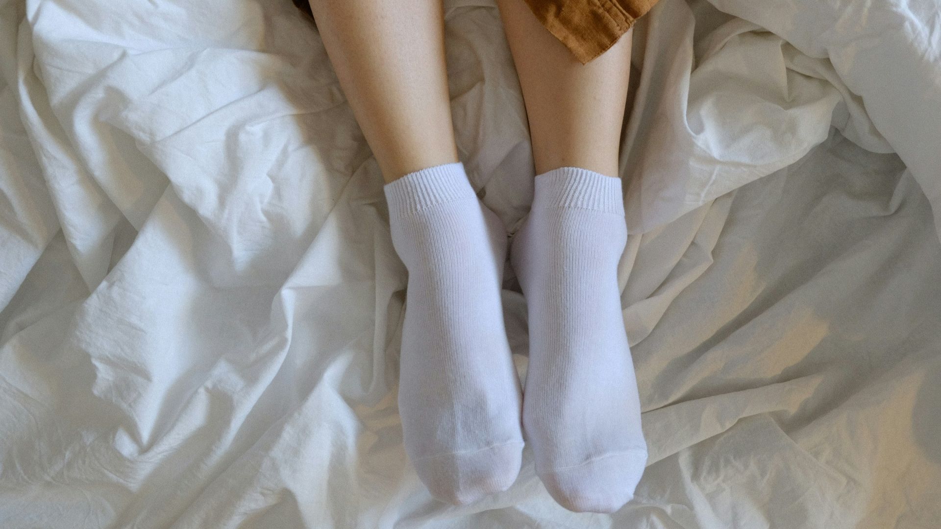 person wearing white socks on white textile