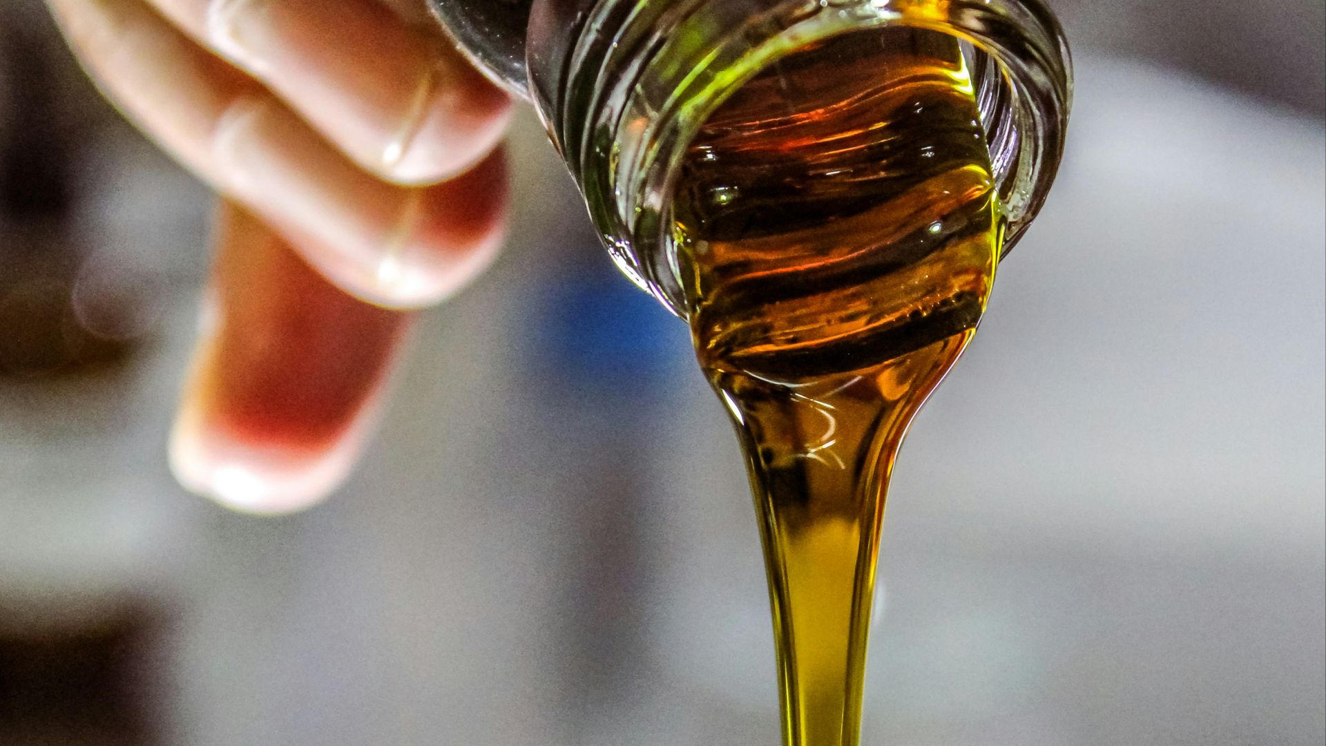person holding clear drinking glass with brown liquid