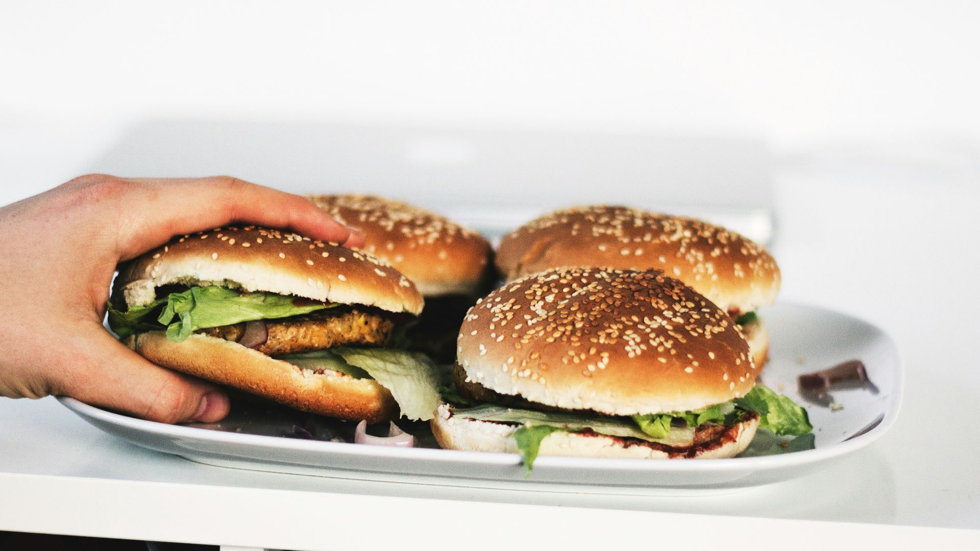person holding hamburger on plate
