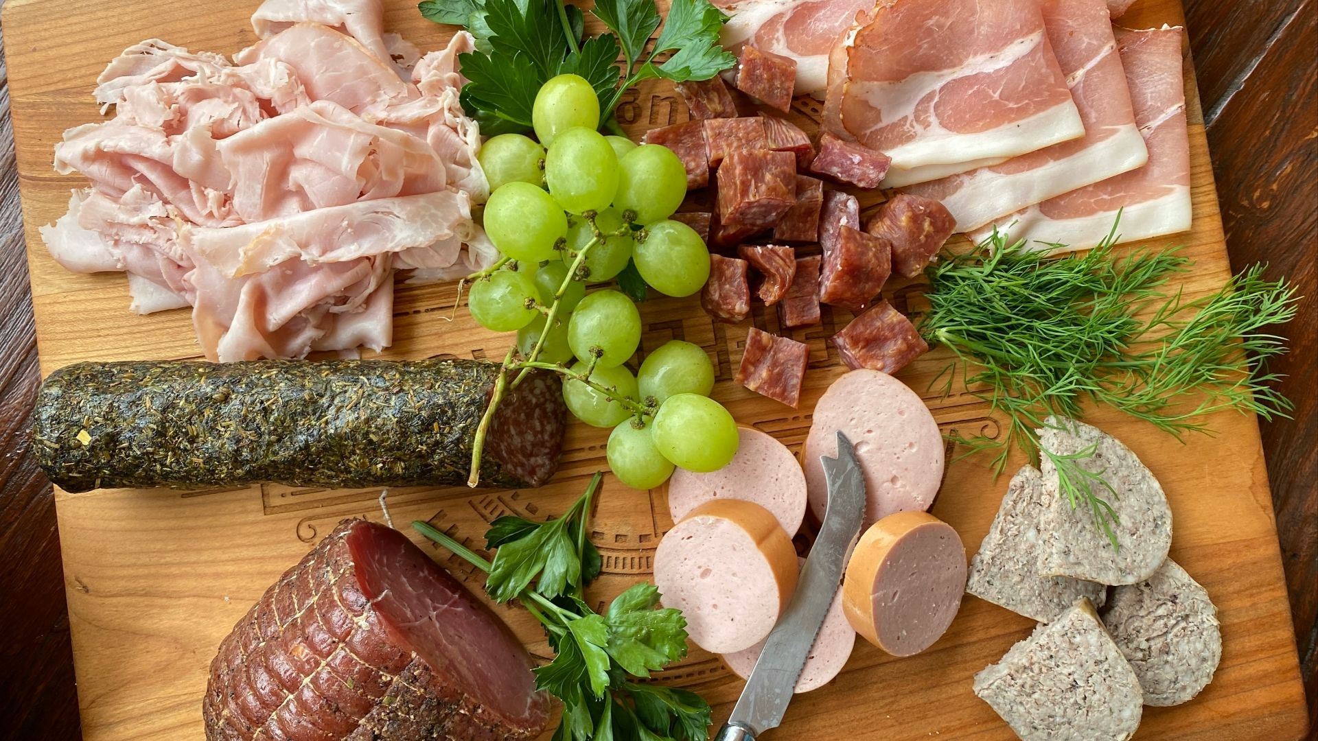 a wooden cutting board topped with meats and cheeses