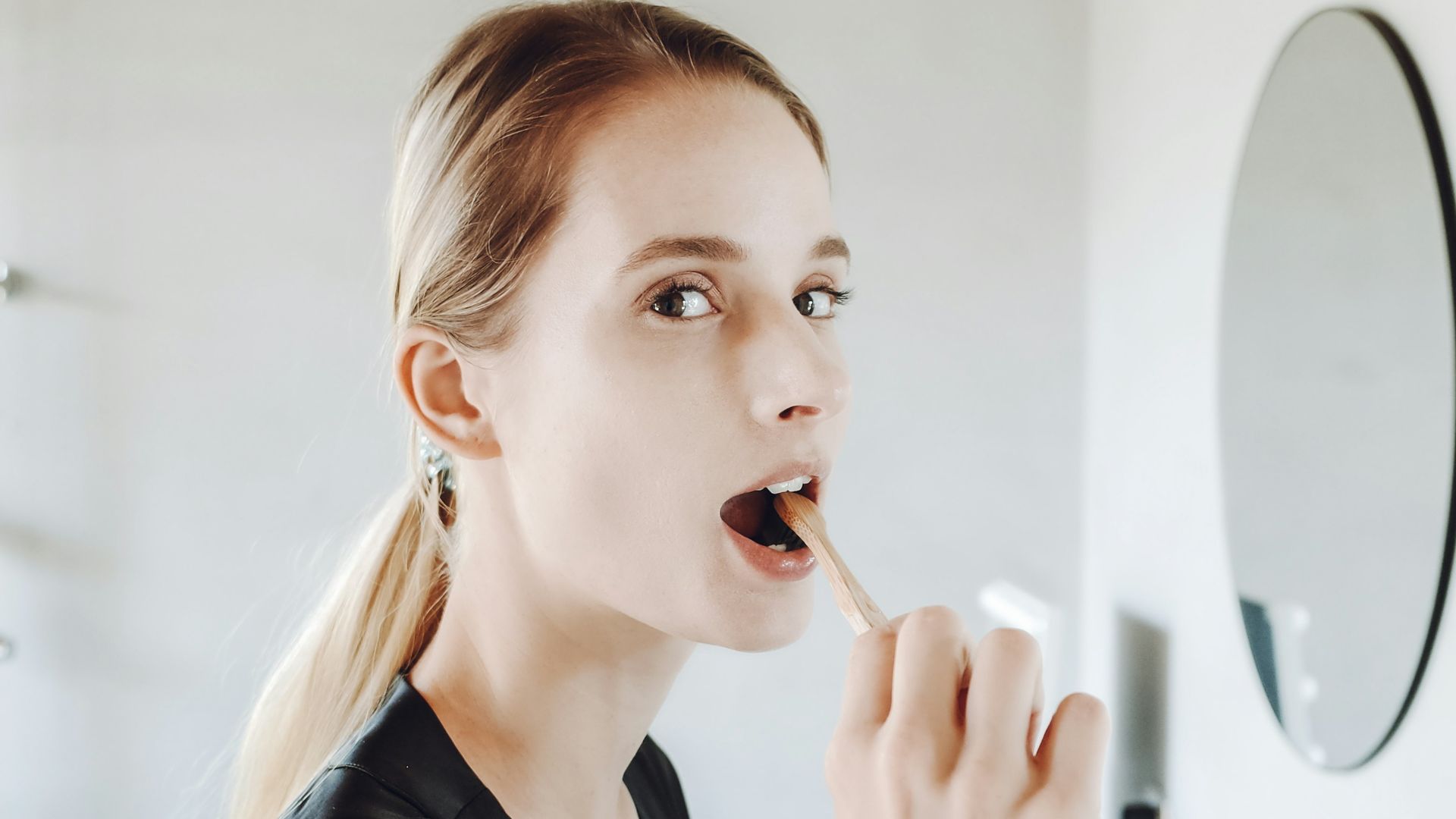 a woman brushing her teeth in front of a mirror