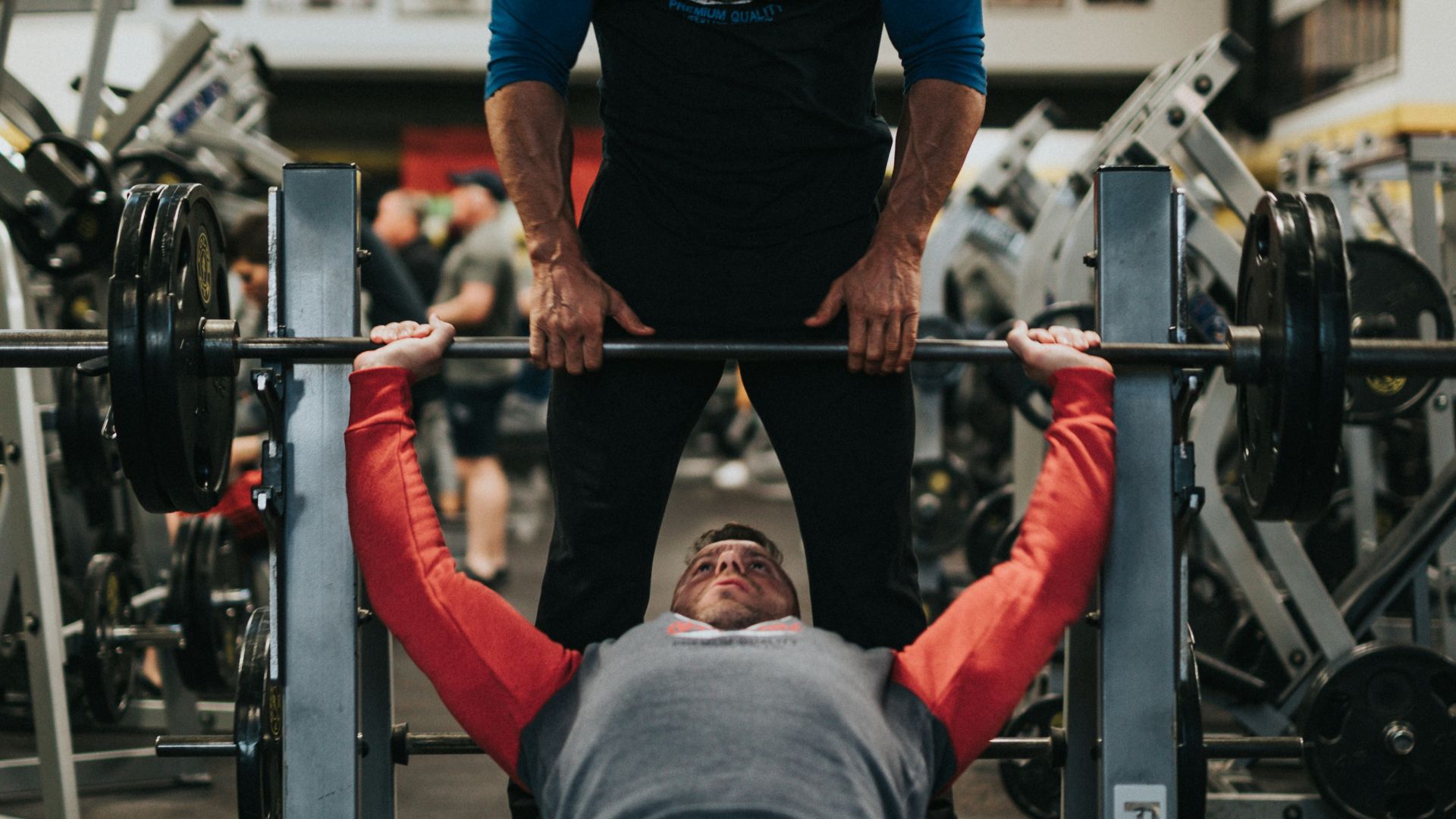man in black crew neck t-shirt and gray pants sitting on black and red bench