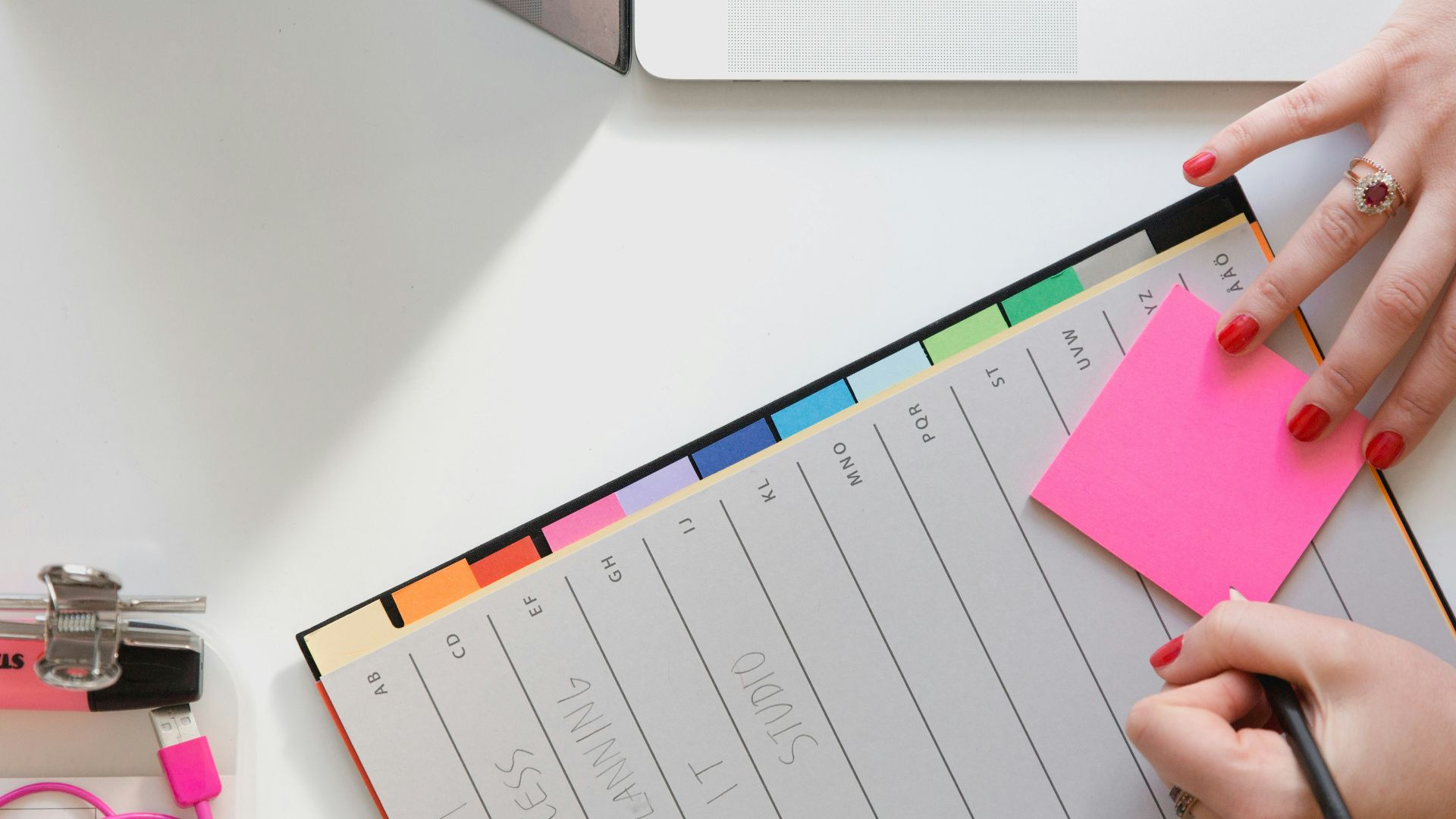 person holding pencil and stick note beside table