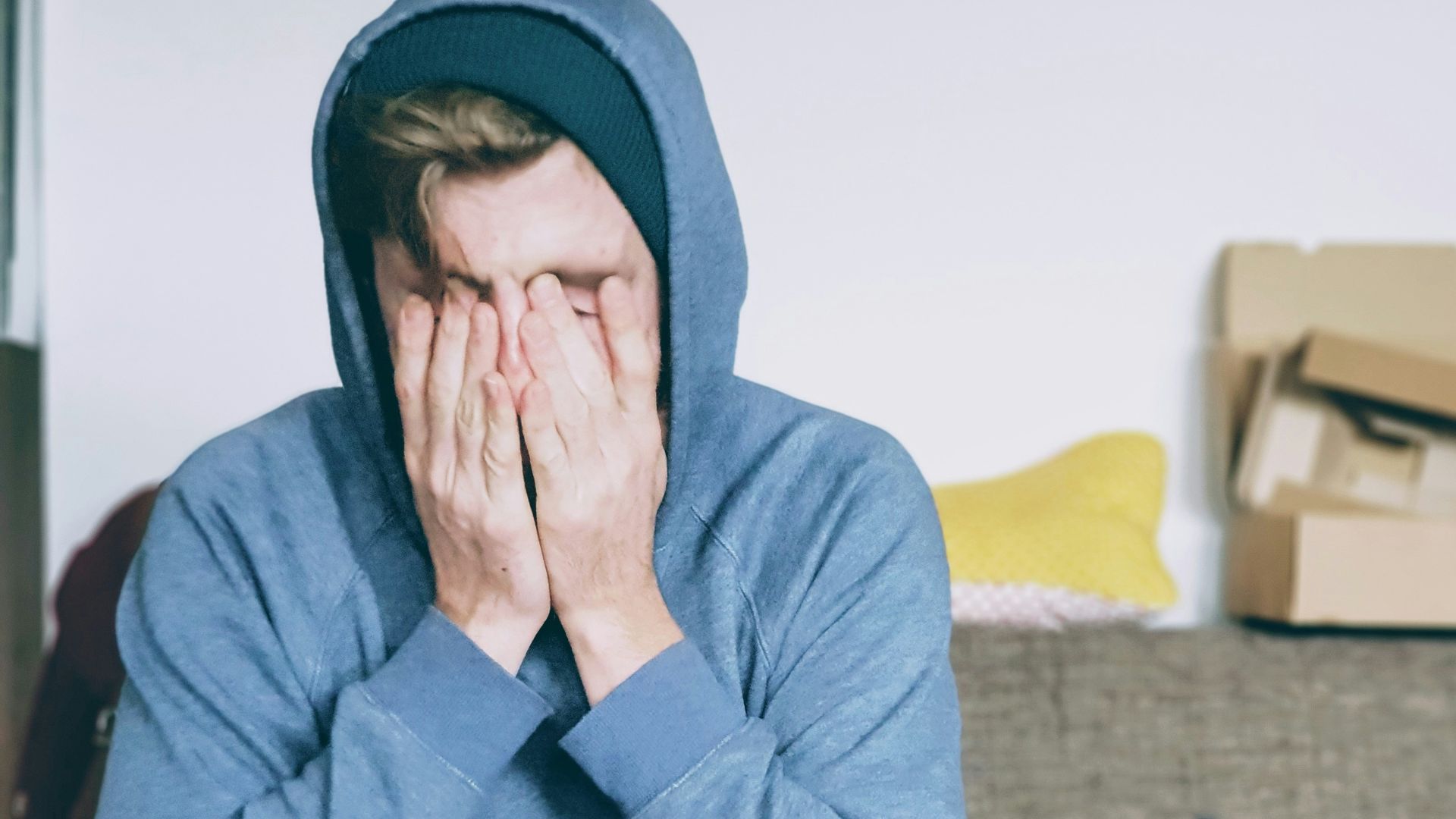 man covering face with both hands while sitting on bench