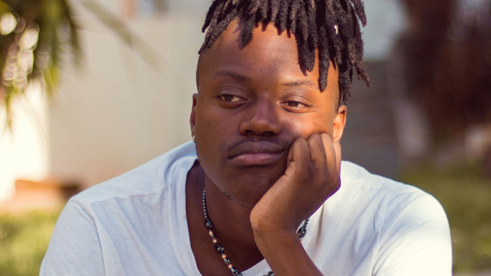 man in white crew neck t-shirt sitting on brown wooden chair
