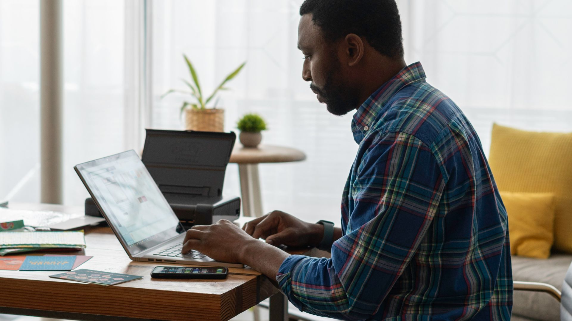 man in blue and white plaid dress shirt sitting on chair using laptop computer
