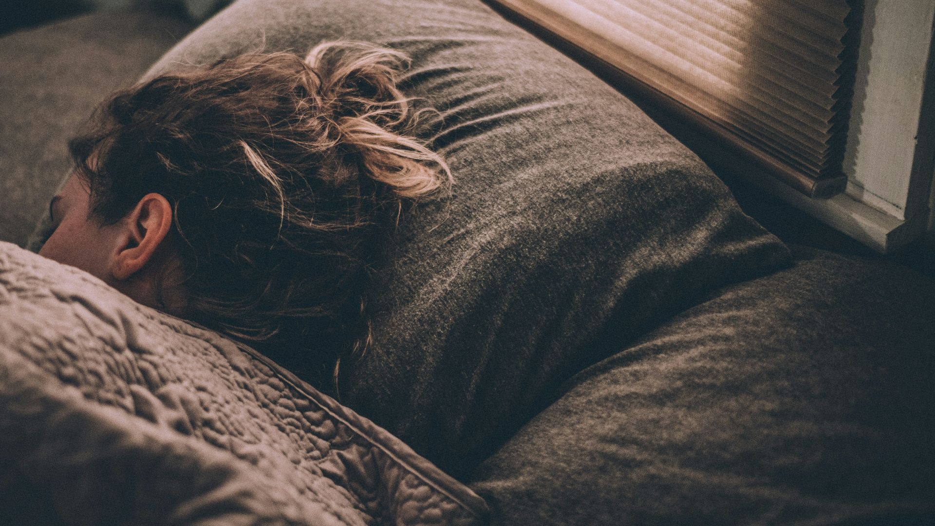 woman sleeping on bed under blankets