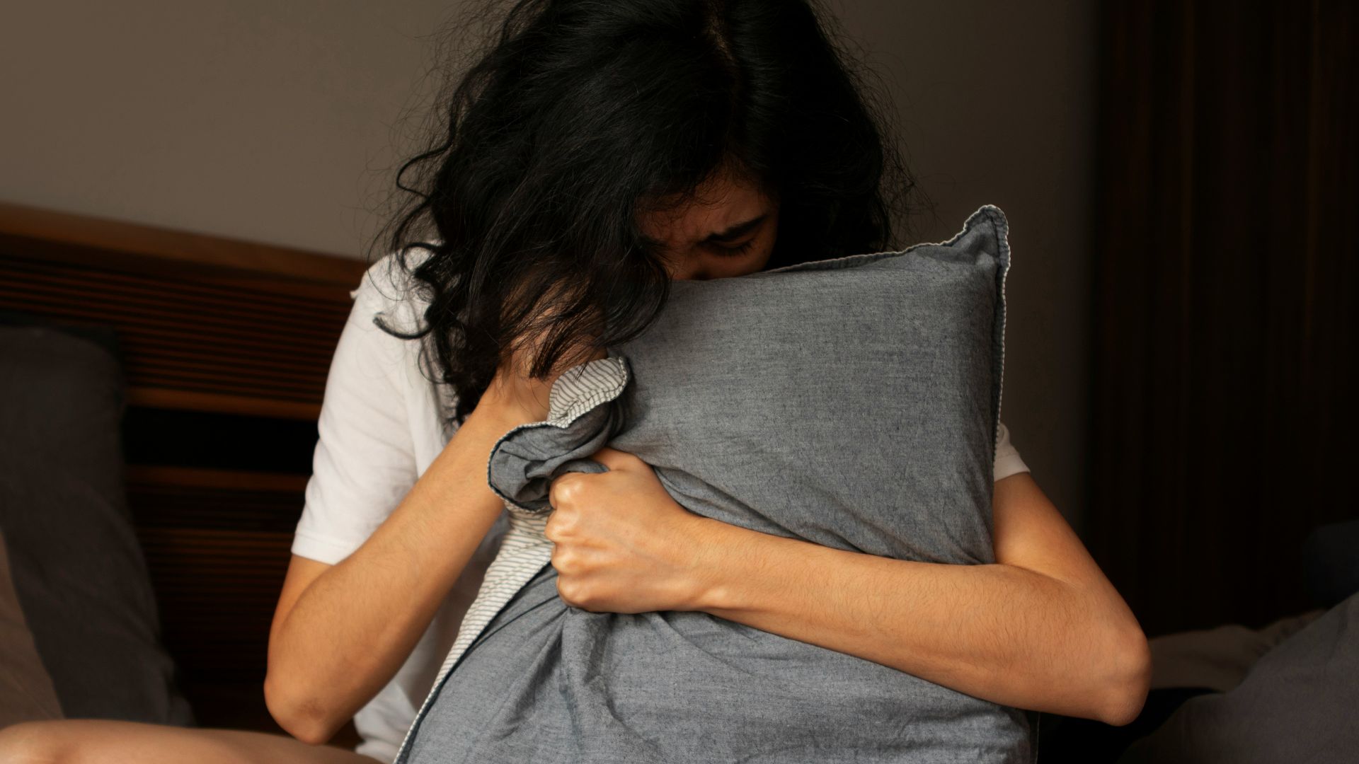 A woman sitting on a bed holding a pillow
