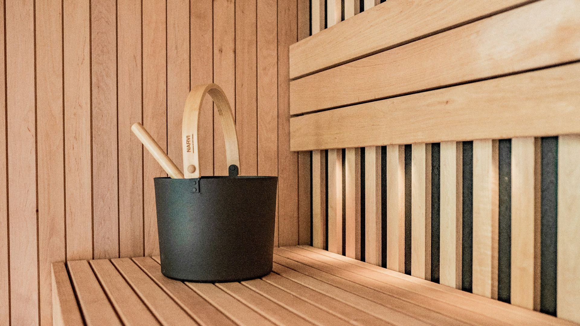 a wooden sauna with a black bucket and two wooden spoons
