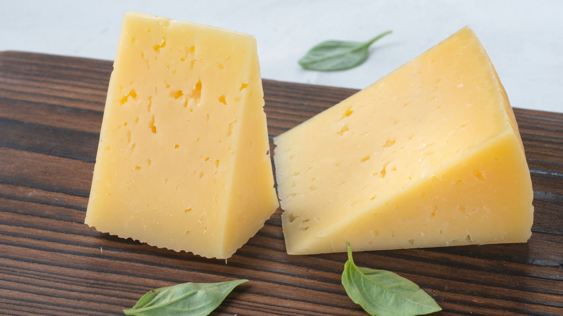 a couple of pieces of cheese sitting on top of a wooden cutting board