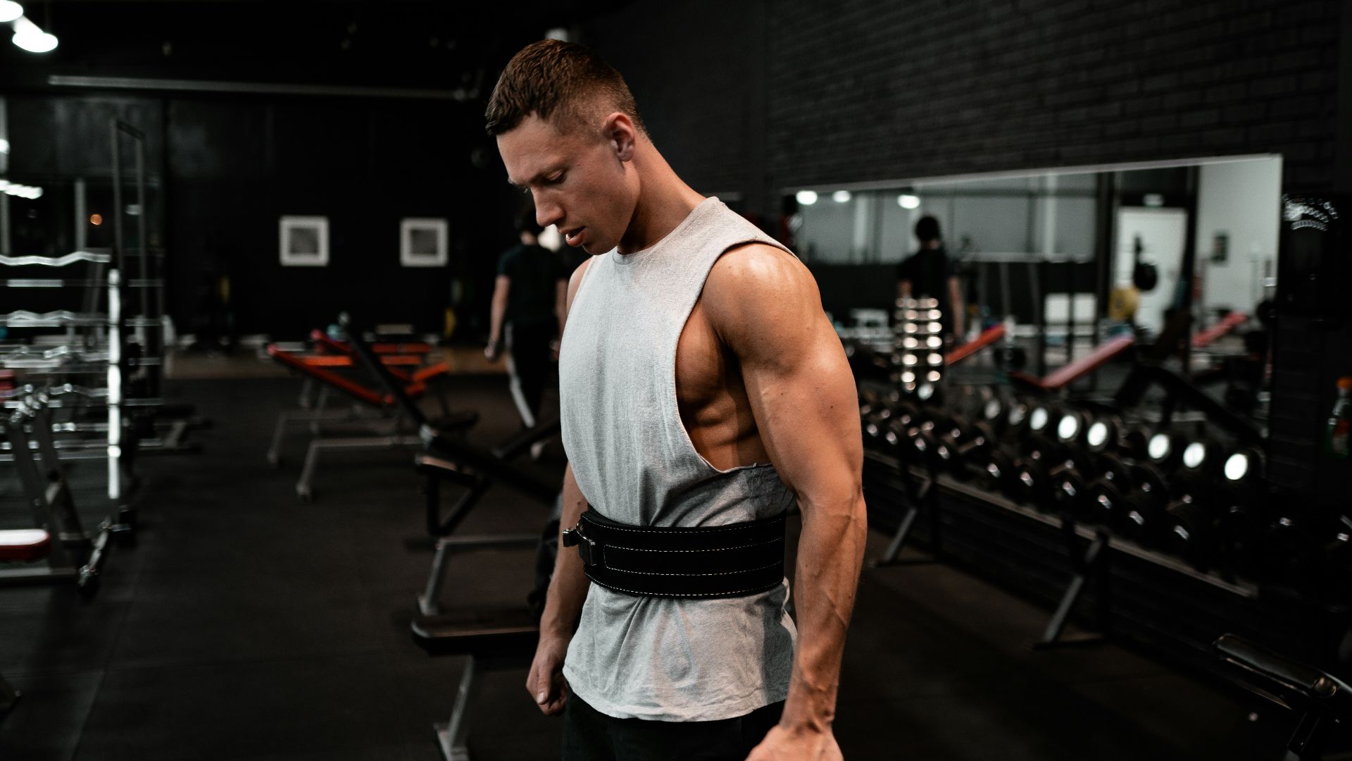 man in white tank top holding bumper plate