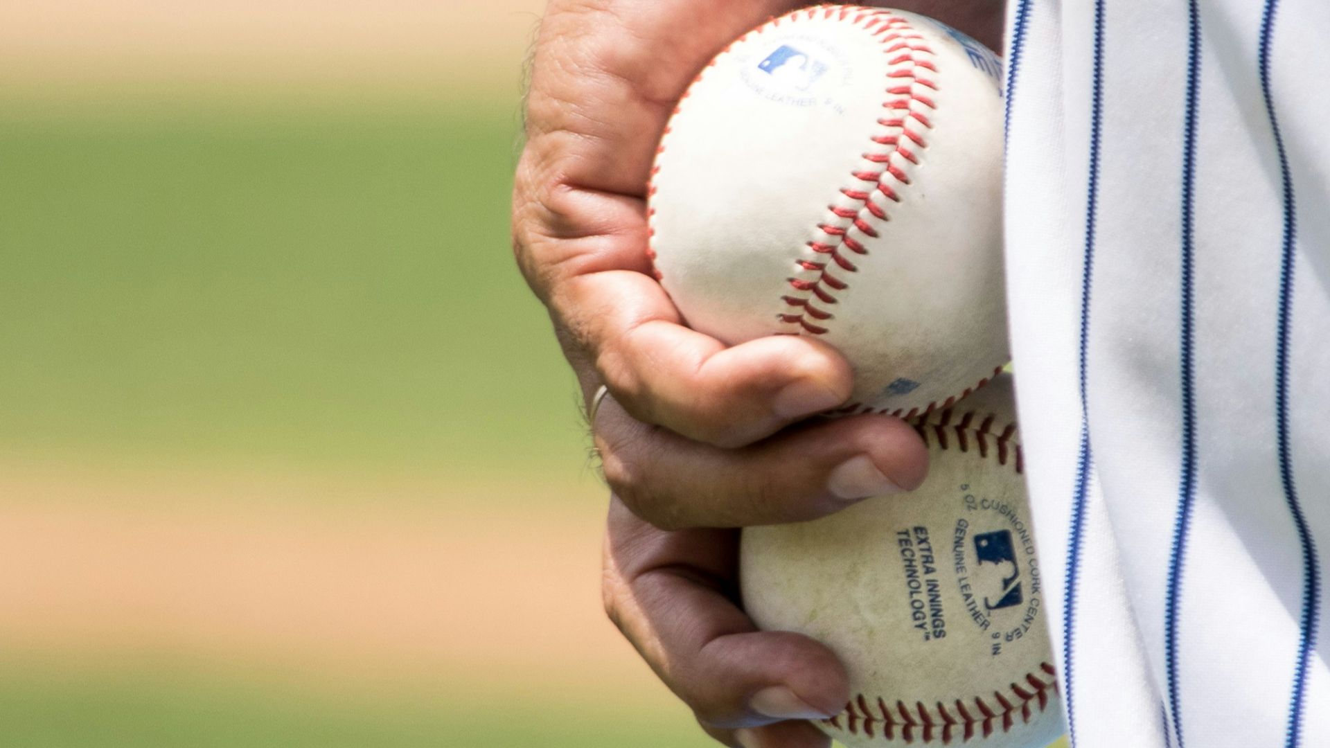 man holding two white baseballs