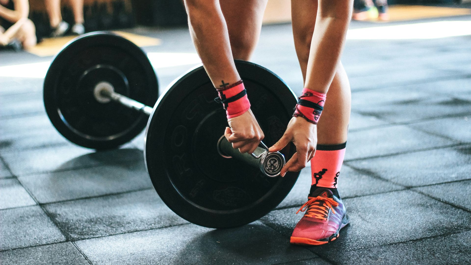 person locking gym plates on barbell